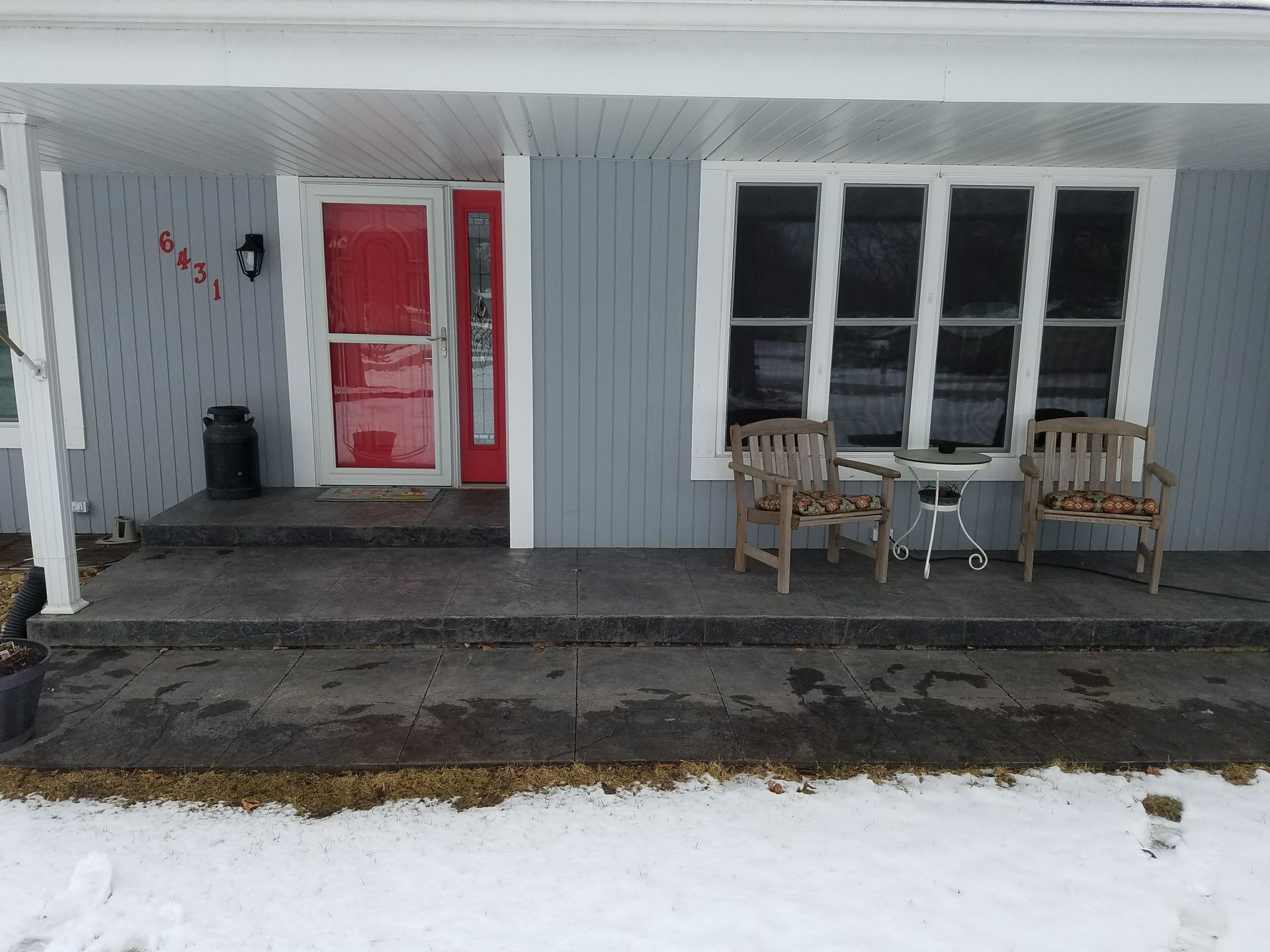 There is a porch with a table and chairs on it.