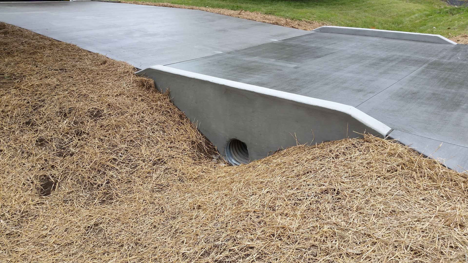 A concrete curb with a hole in the middle of it