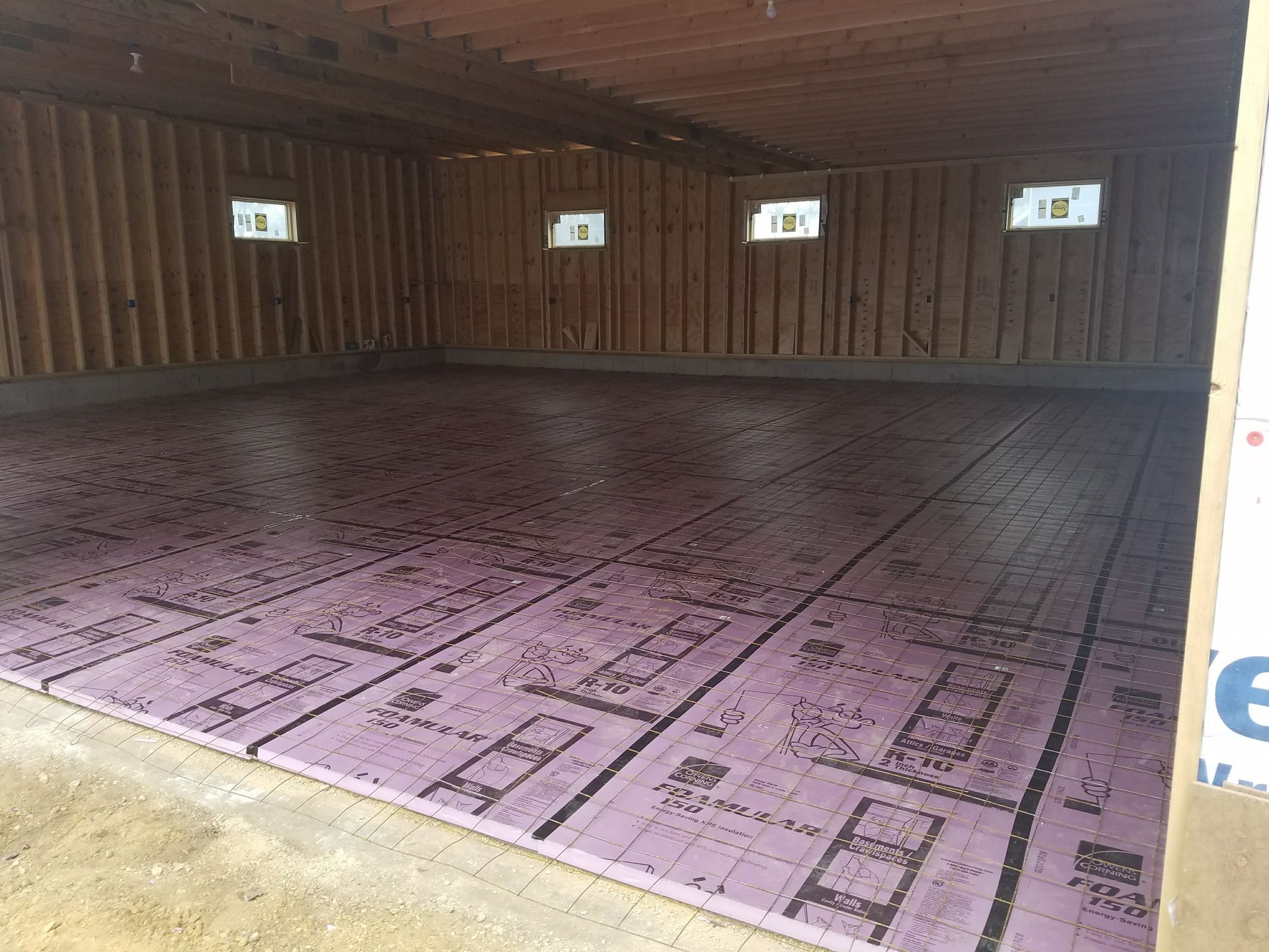 The inside of a garage with purple insulation on the floor.