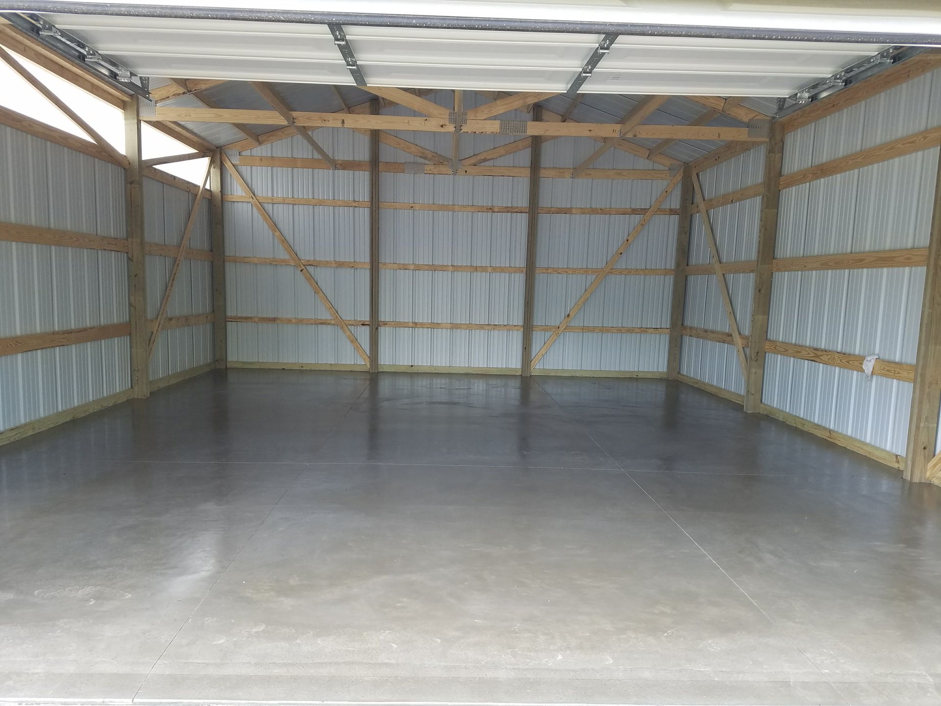 An empty garage with a concrete floor and wooden walls.