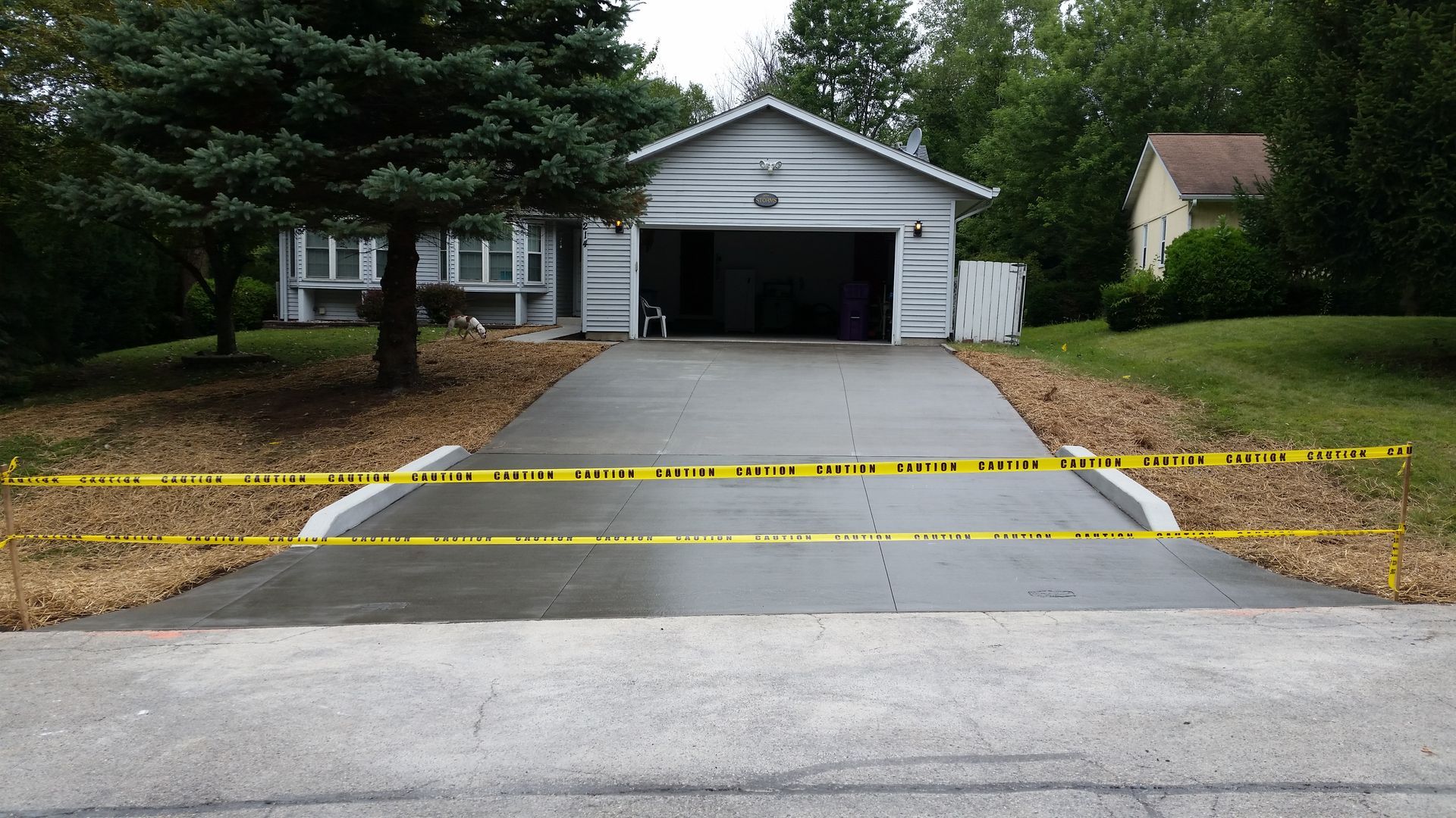 A concrete driveway in front of a house with yellow tape on it