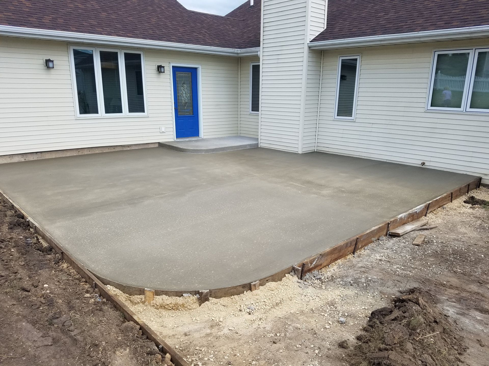 A concrete patio is being built in front of a house.