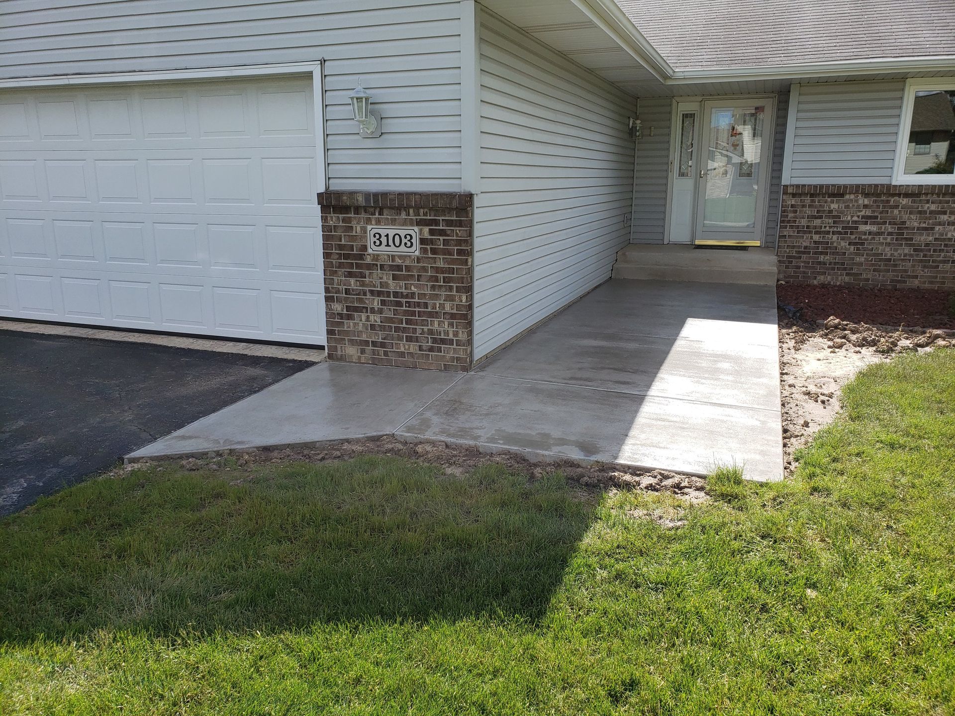 A white house with a concrete walkway leading to the front door.