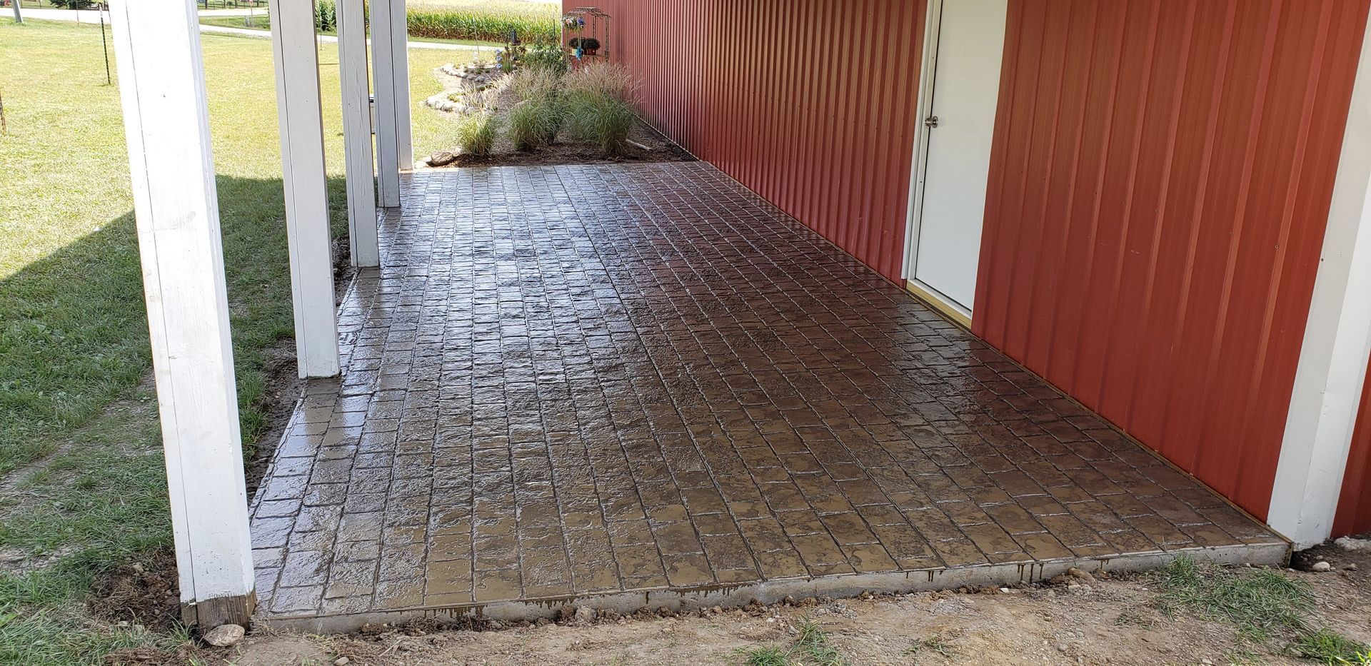 A concrete walkway is being built in front of a red barn.