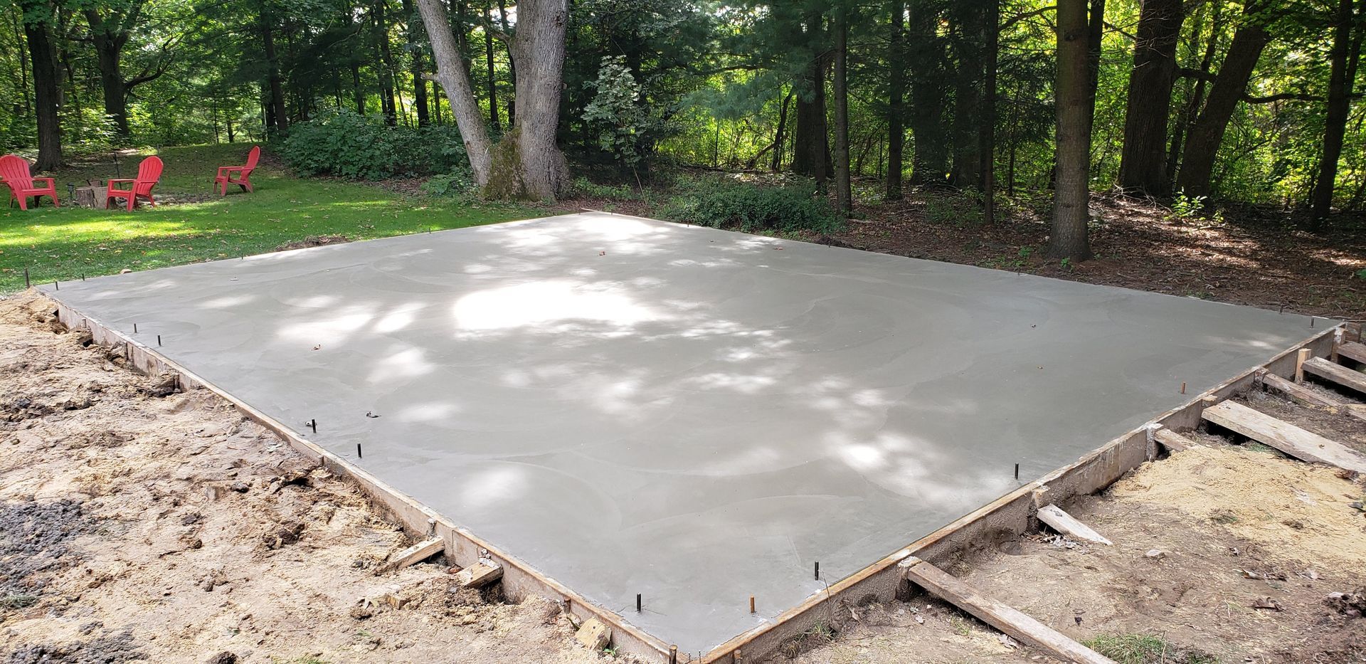 A concrete floor is being built in a backyard in the woods.