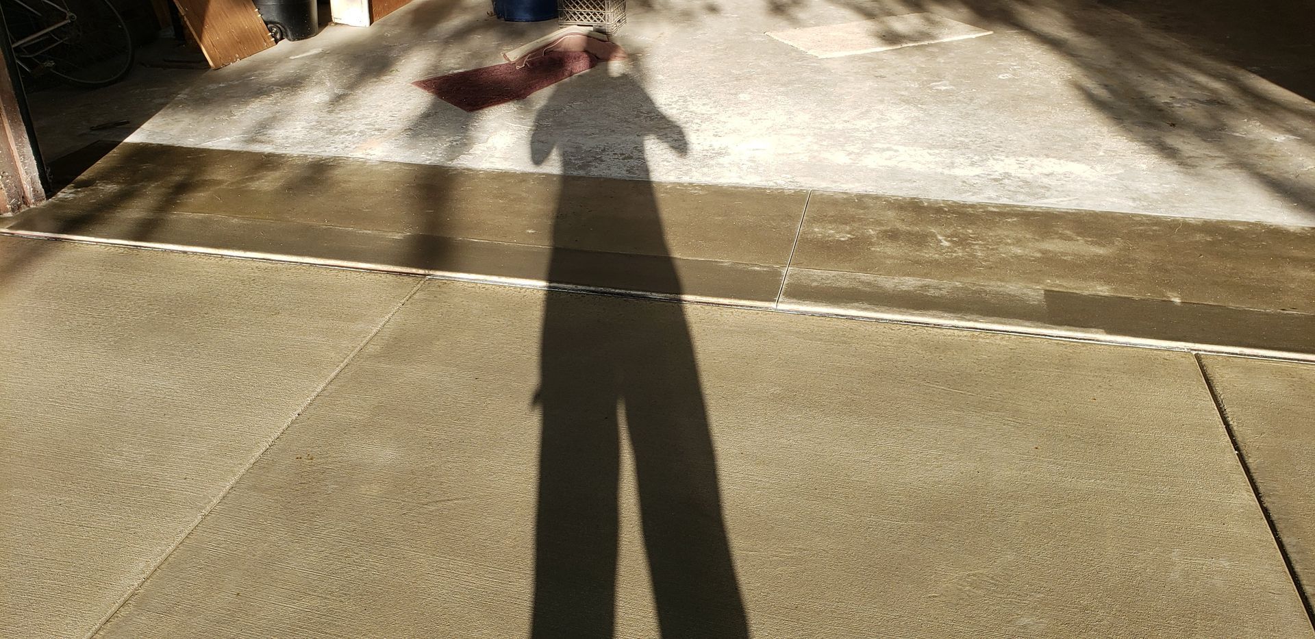 A person 's shadow is cast on the sidewalk.
