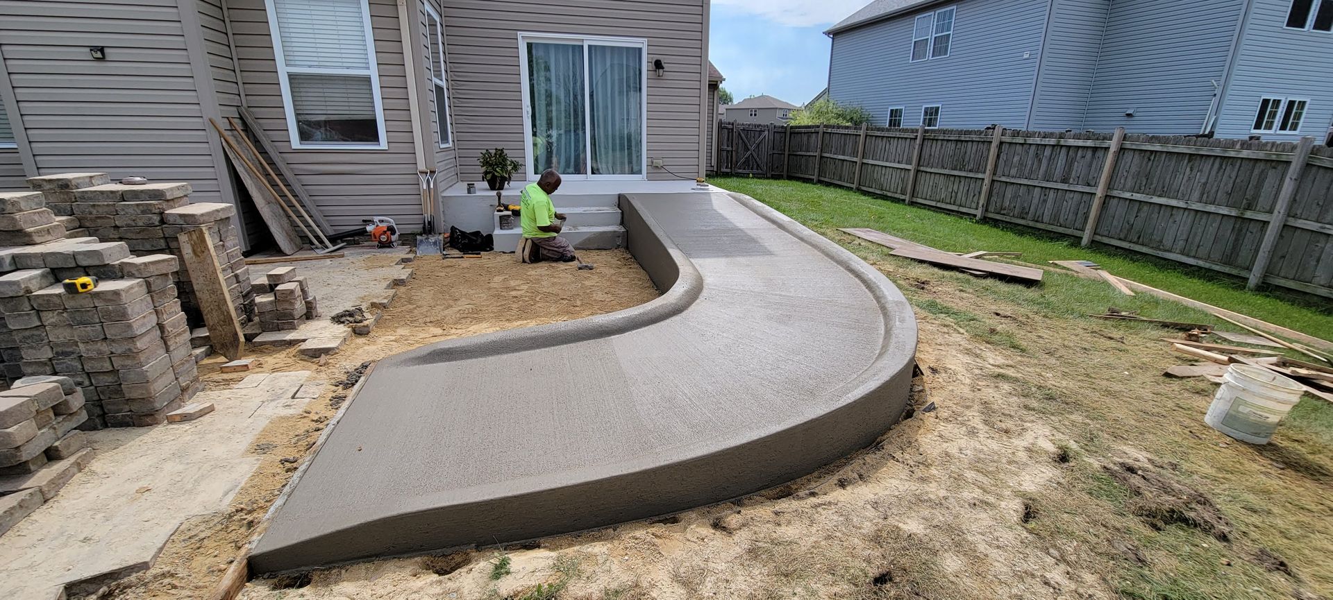 A concrete walkway is being built in the backyard of a house.