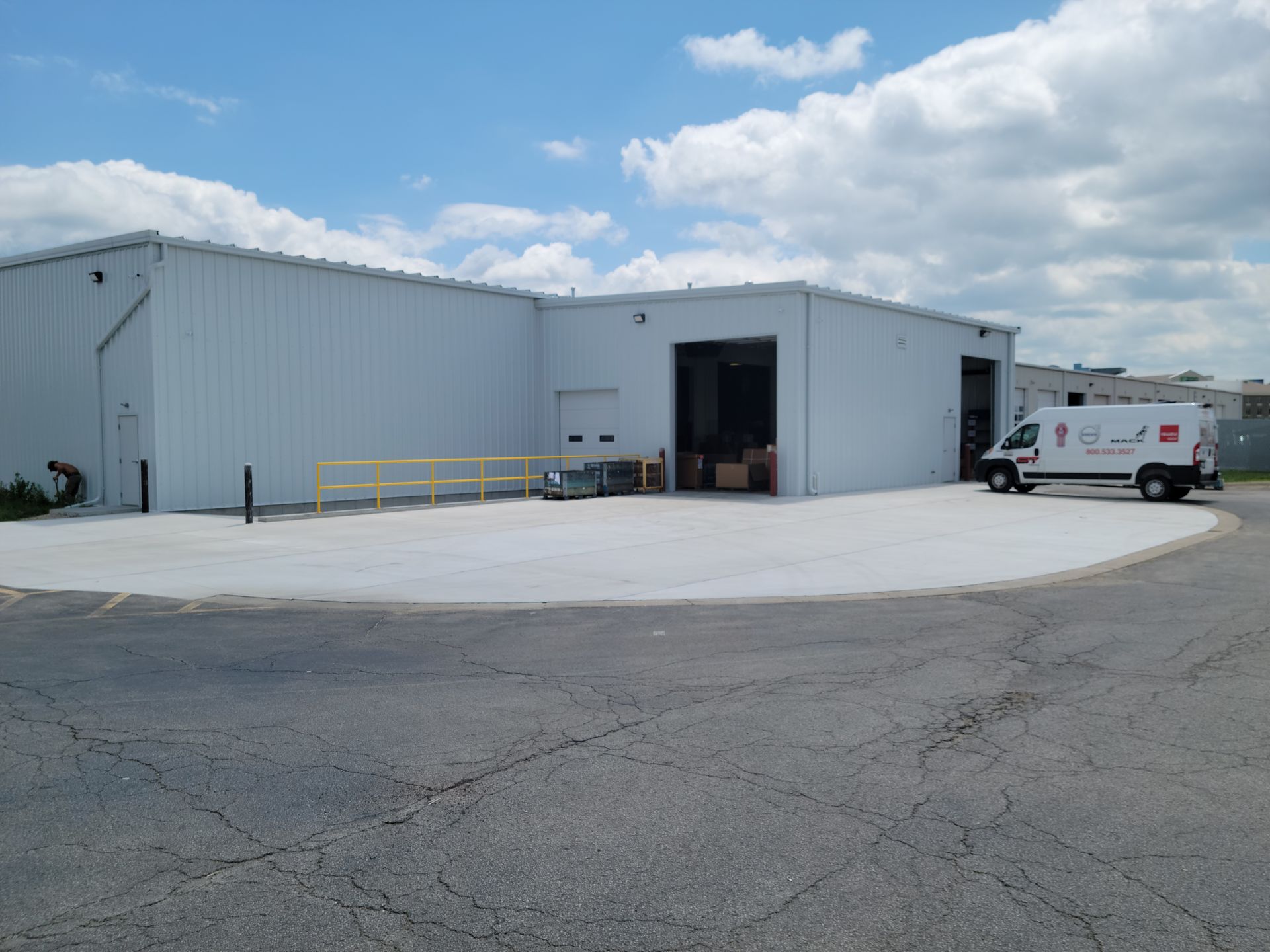 A white van is parked in front of a large white building.