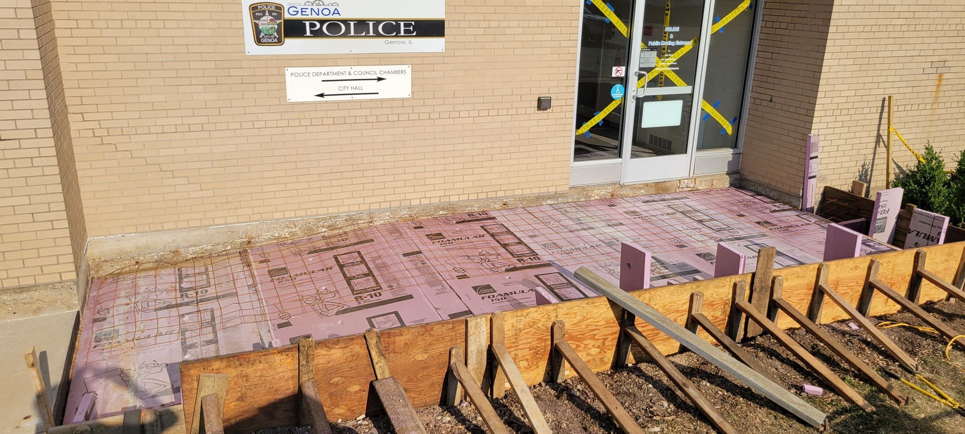 A concrete walkway is being built in front of a brick building.