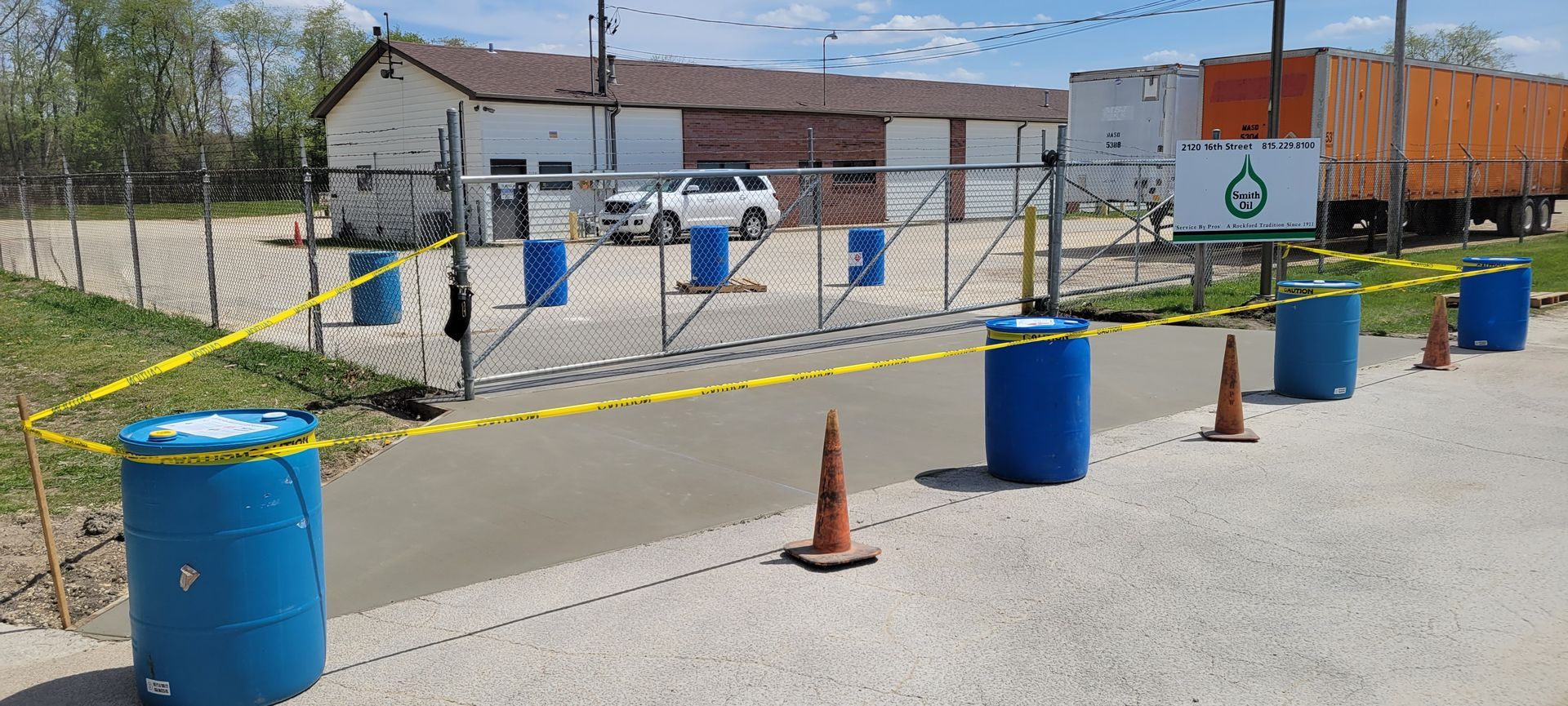 A row of blue barrels and traffic cones on the side of a road.