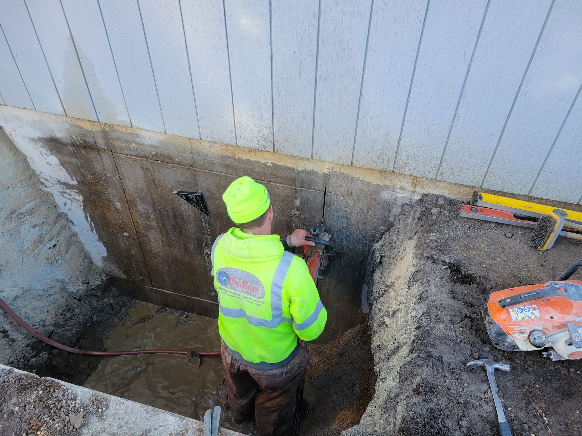 A man is cutting a hole in a wall with a saw.