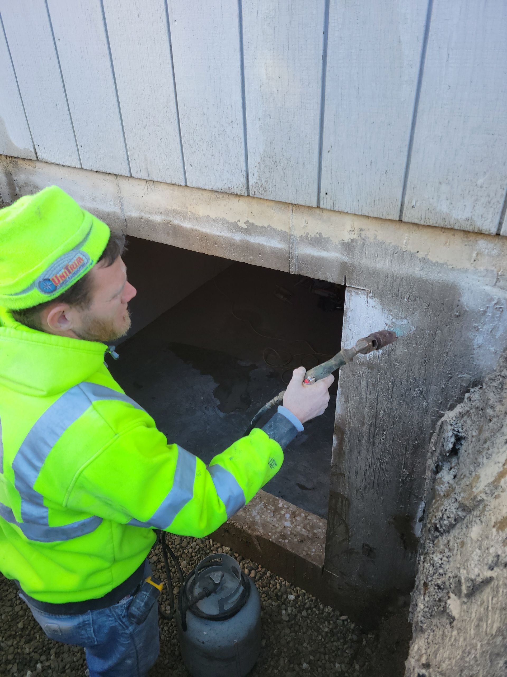 A man in a neon yellow jacket is working on a wall