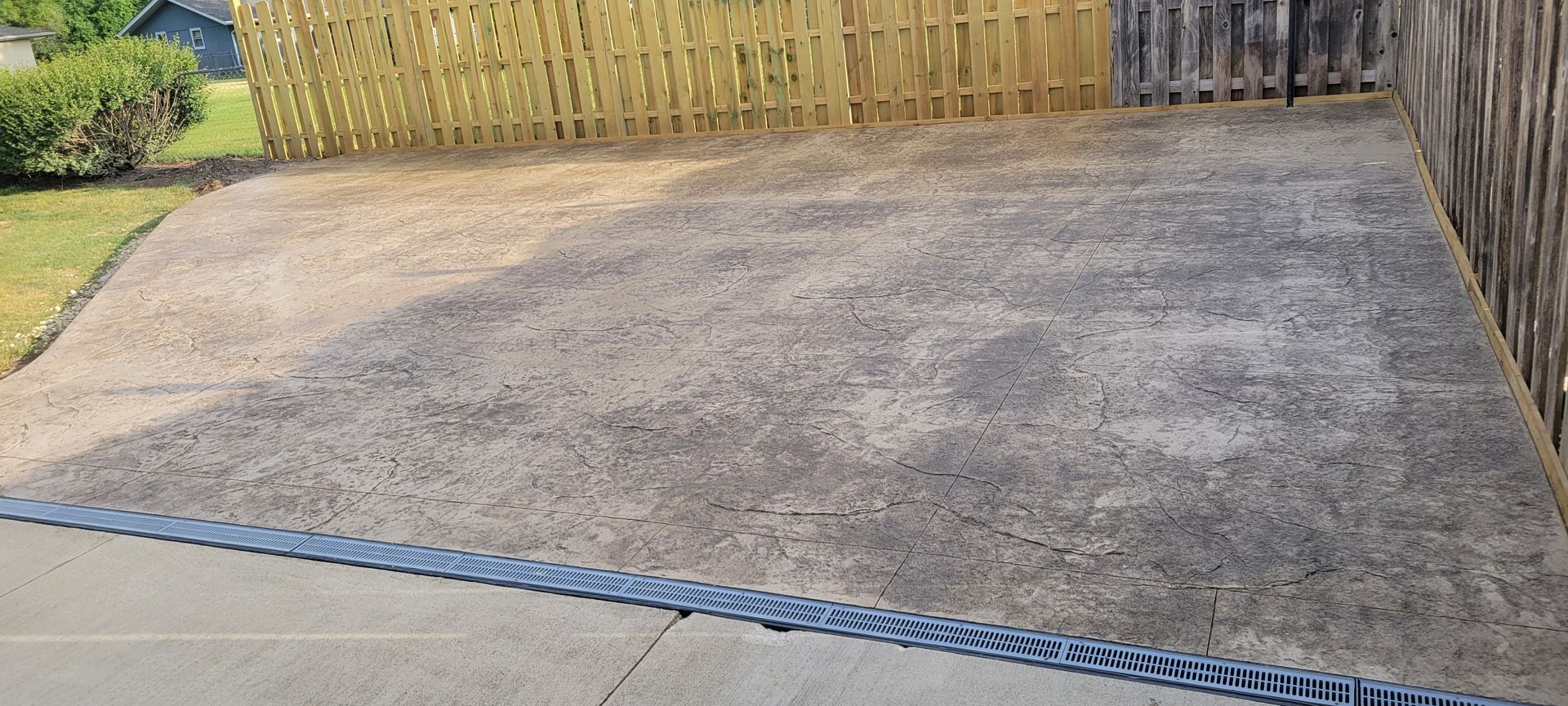 A concrete driveway with a wooden fence in the background.