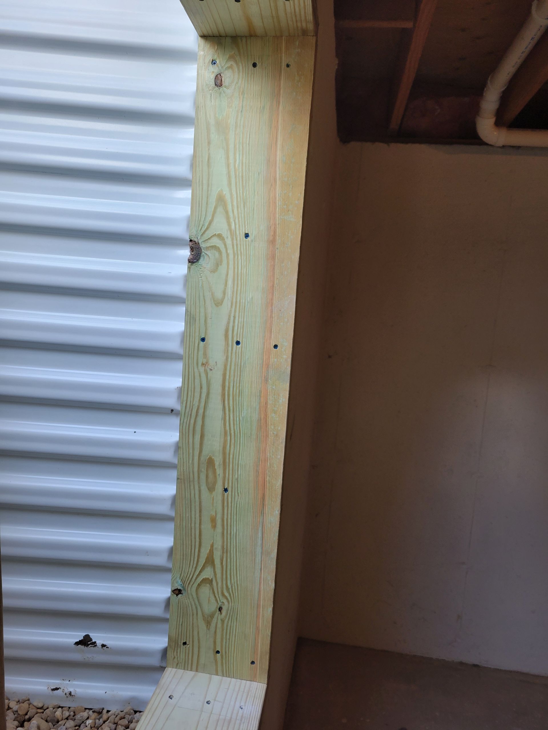 A wooden beam is sitting in a room next to a white wall.