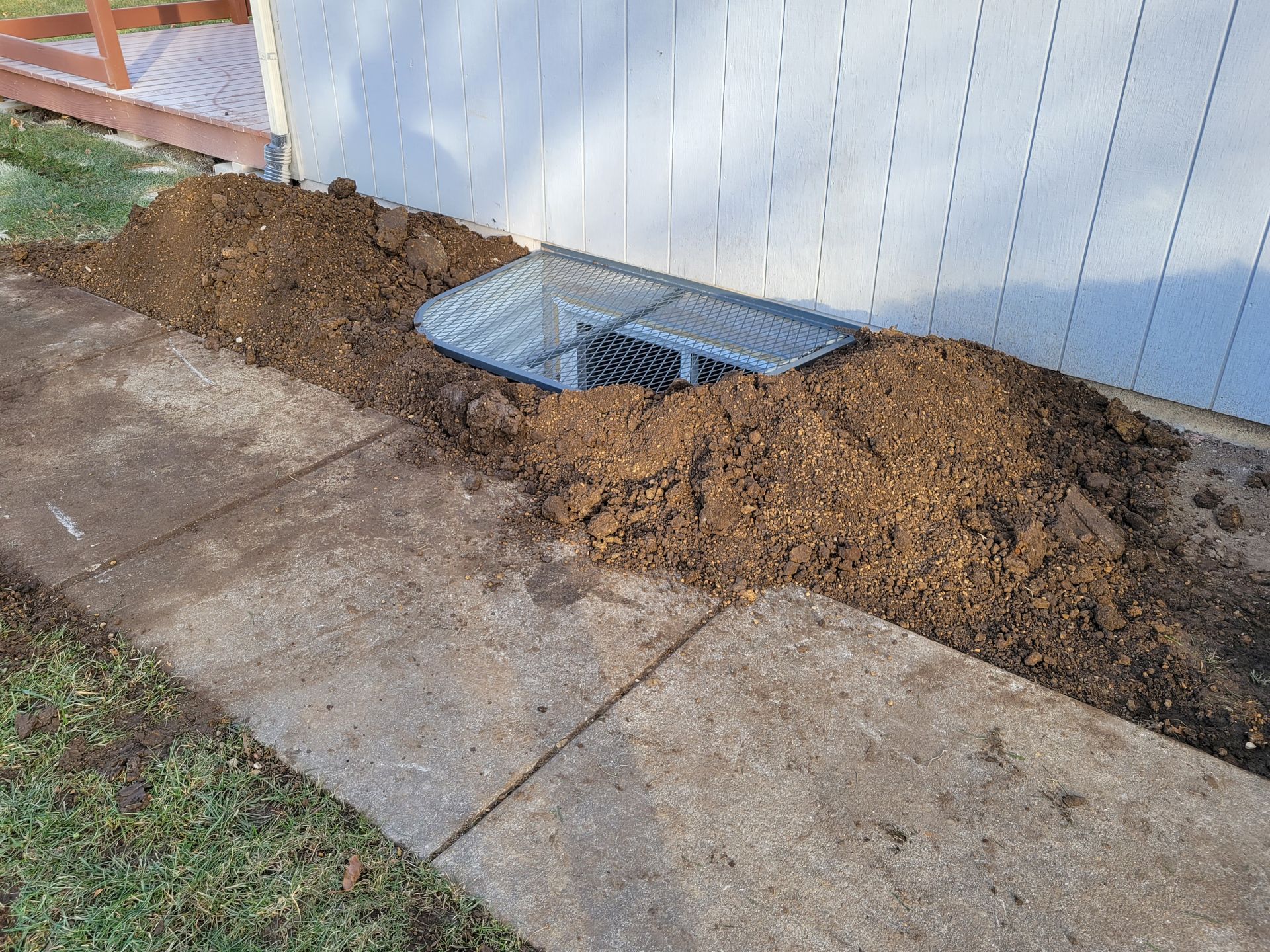 A window well is being installed on the side of a house.