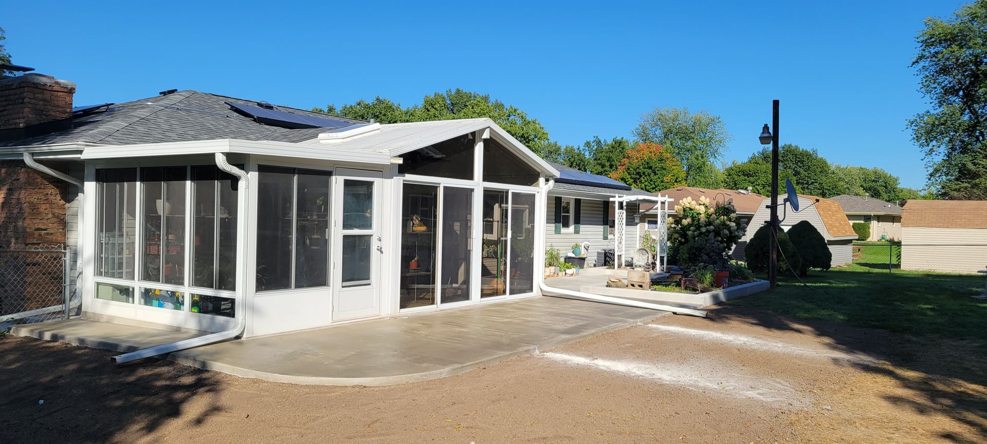 A house with a screened in porch and a driveway in front of it.