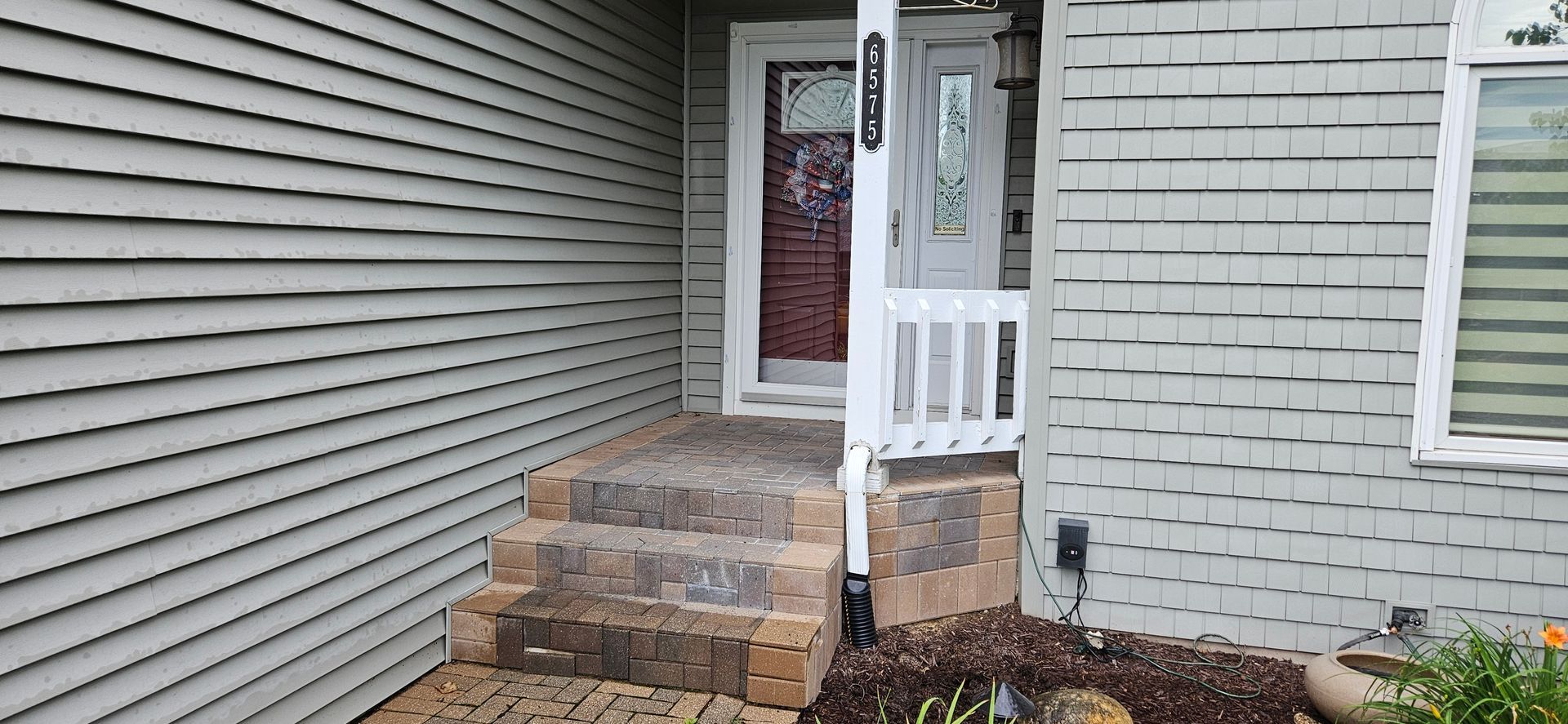 A white brick house with a porch and stairs leading to the front door.
