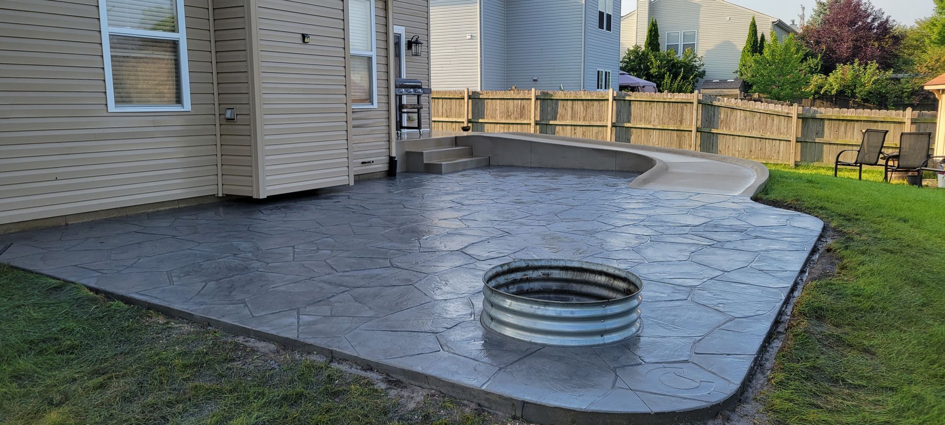 A patio with a fire pit in the middle of it in front of a house.