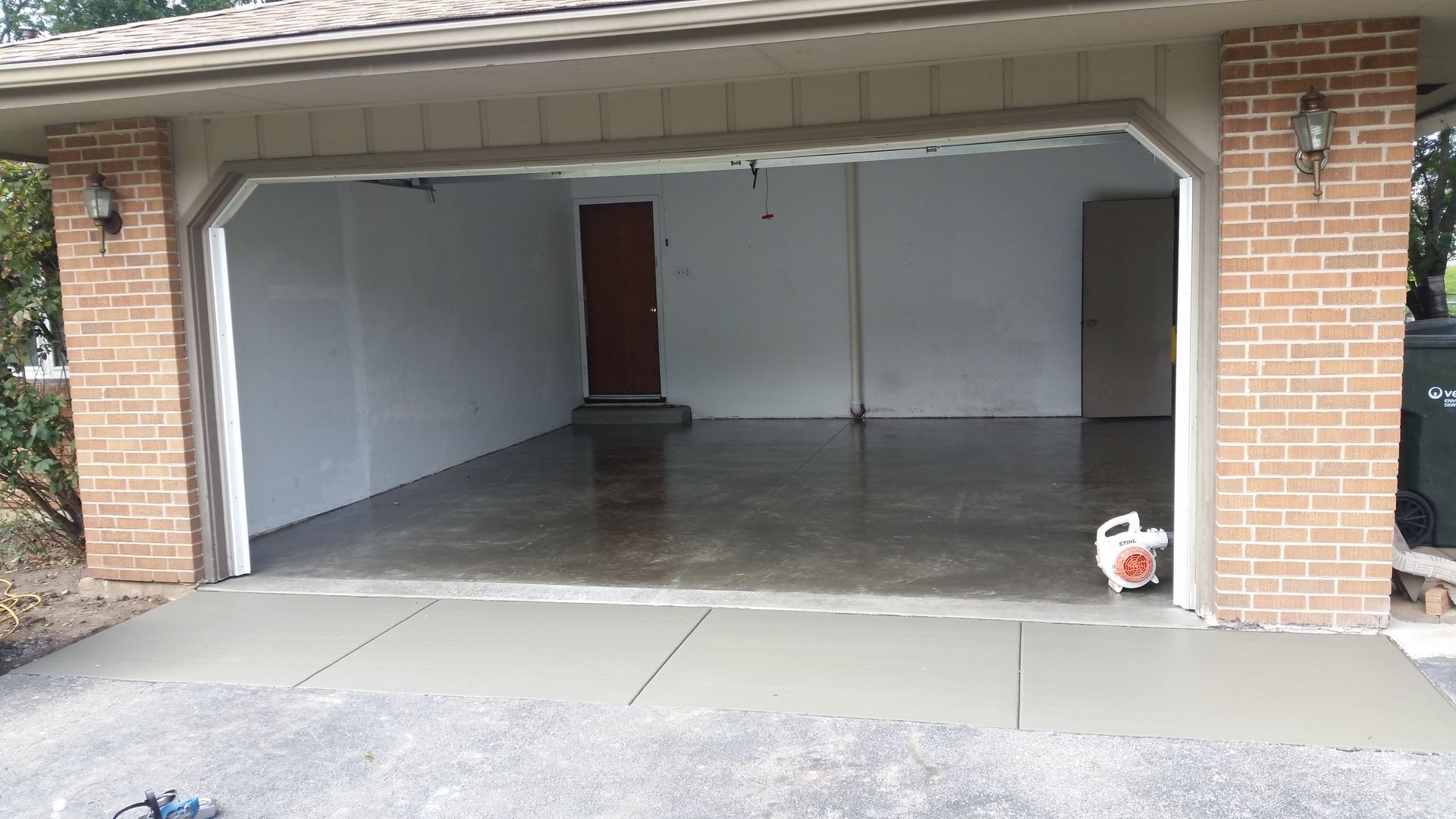 An empty garage with a brick wall and a concrete floor.