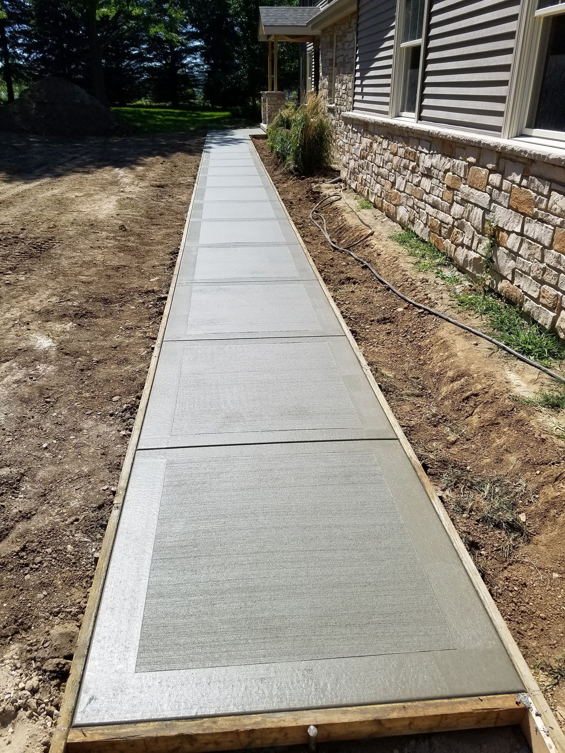 A concrete walkway is being built in front of a house.
