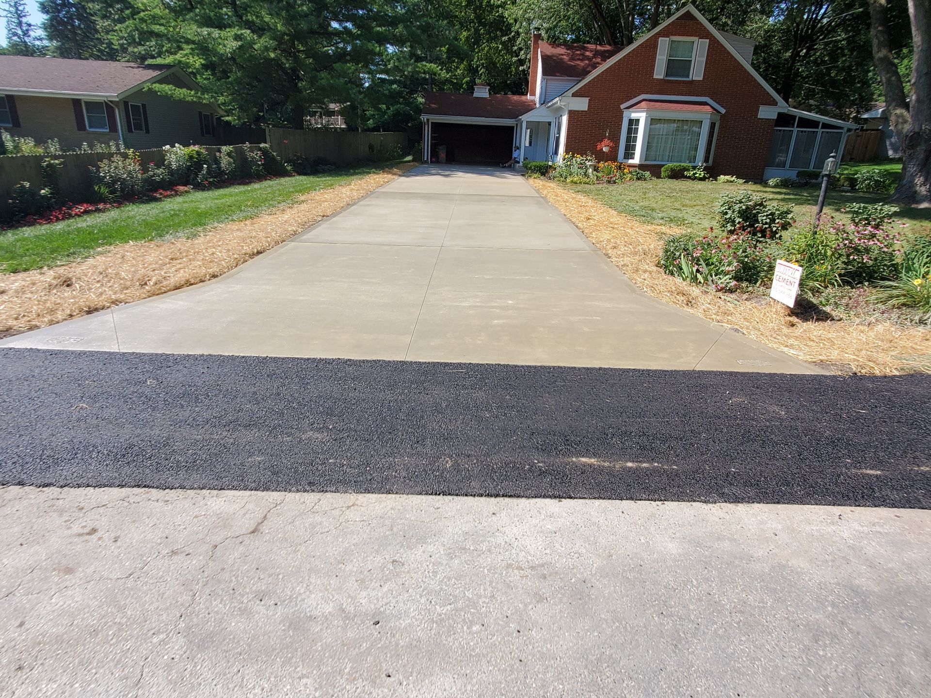 A driveway with a brick house in the background