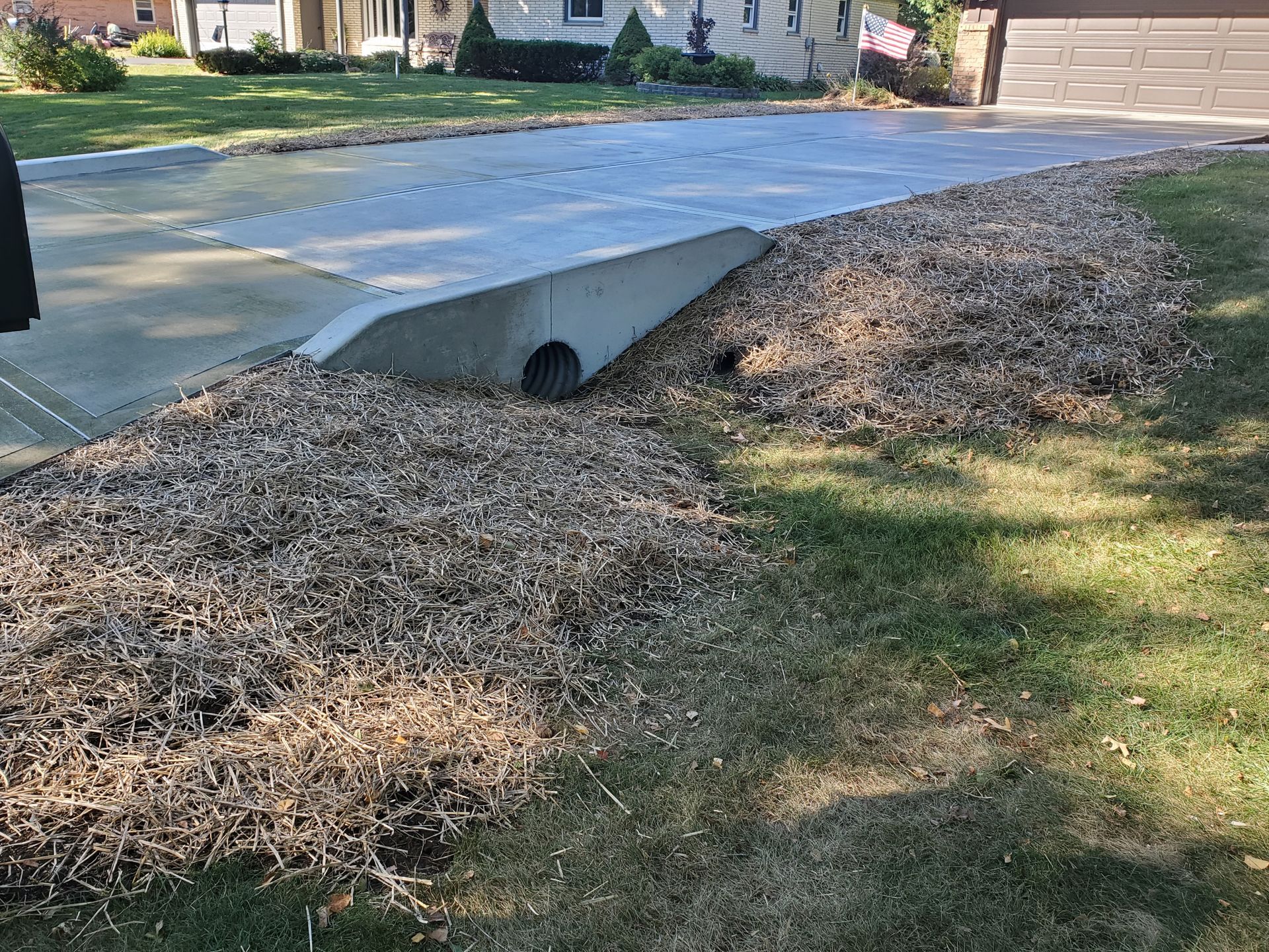 A concrete driveway with a drain in the middle of it.