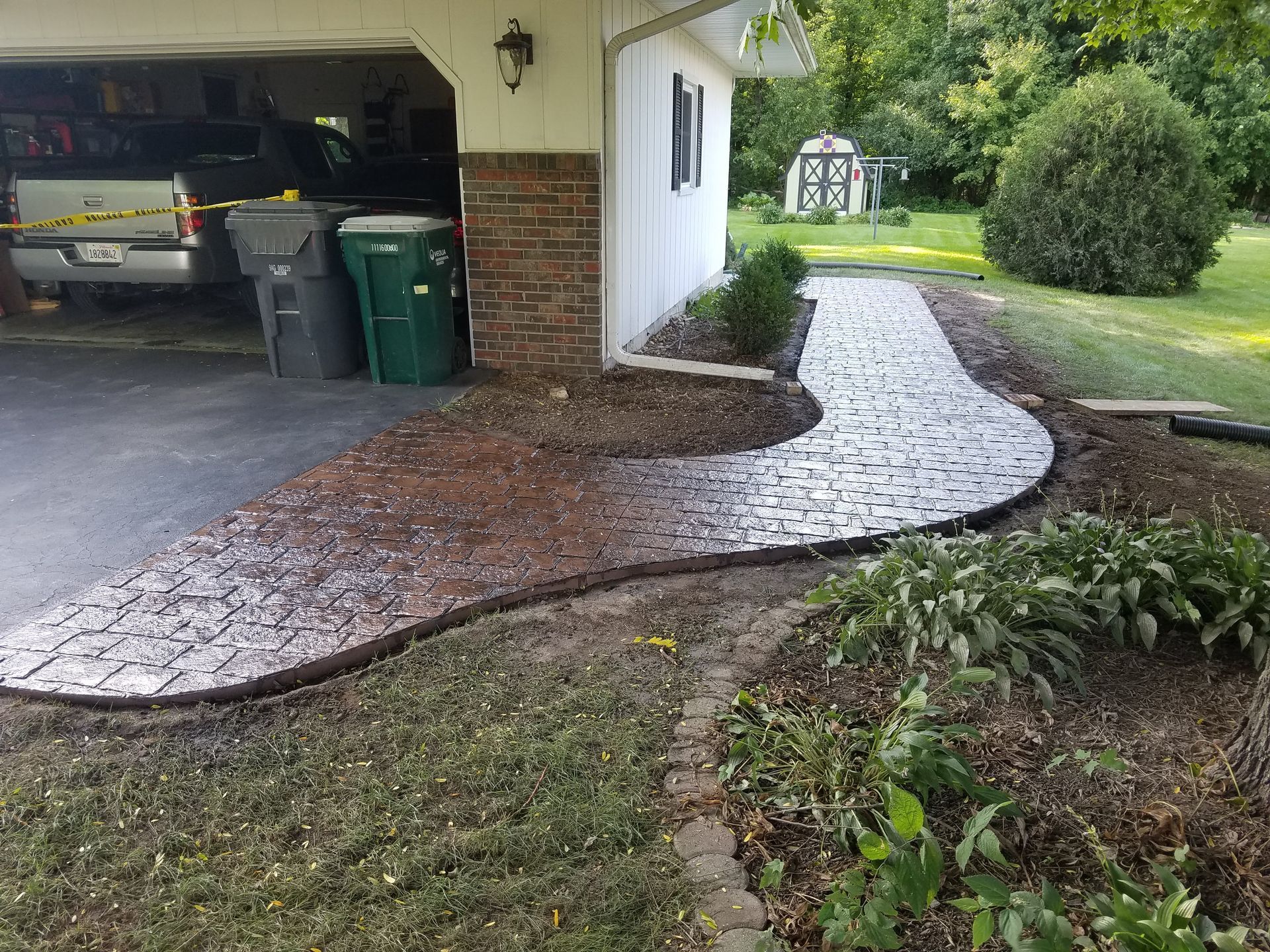 A concrete walkway is being built in front of a garage.