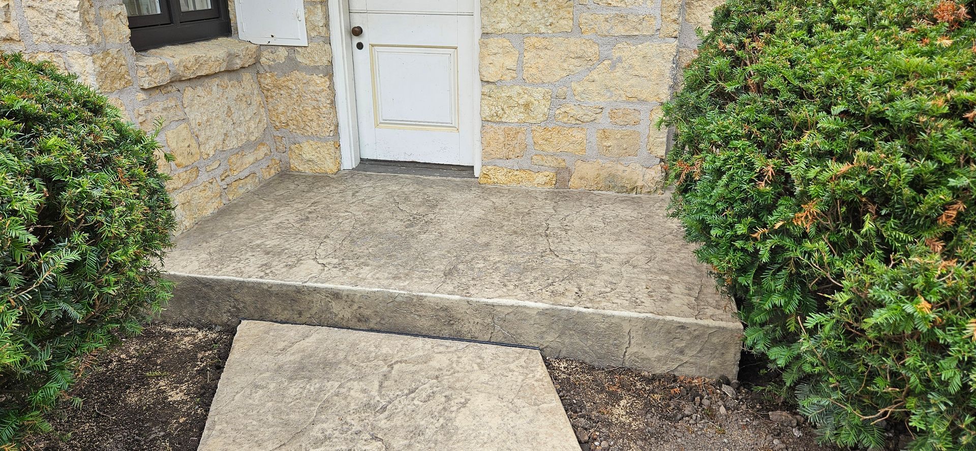 There is a concrete walkway leading to the front door of a house.