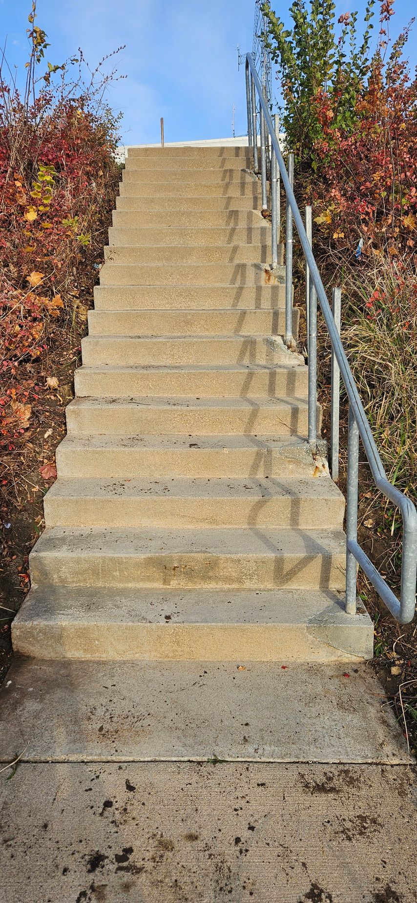 A set of stairs with a metal railing going up a hill.