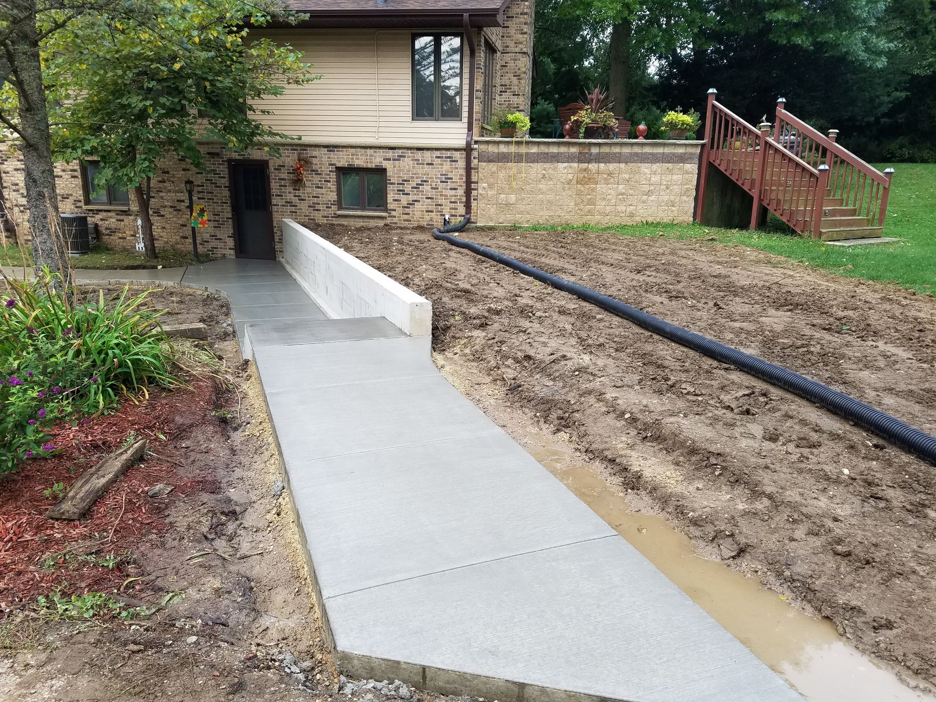 A concrete walkway is being built in front of a house