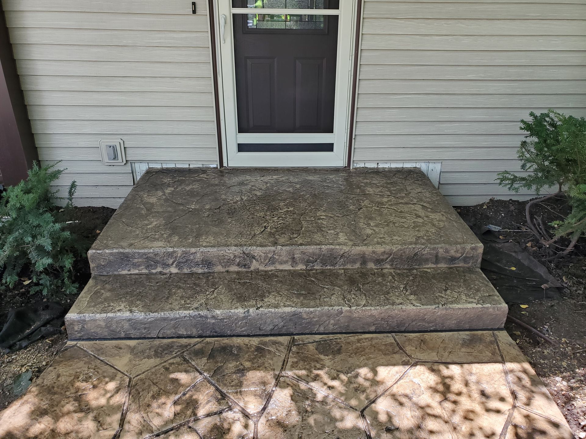 A concrete porch with steps leading to the front door of a house.