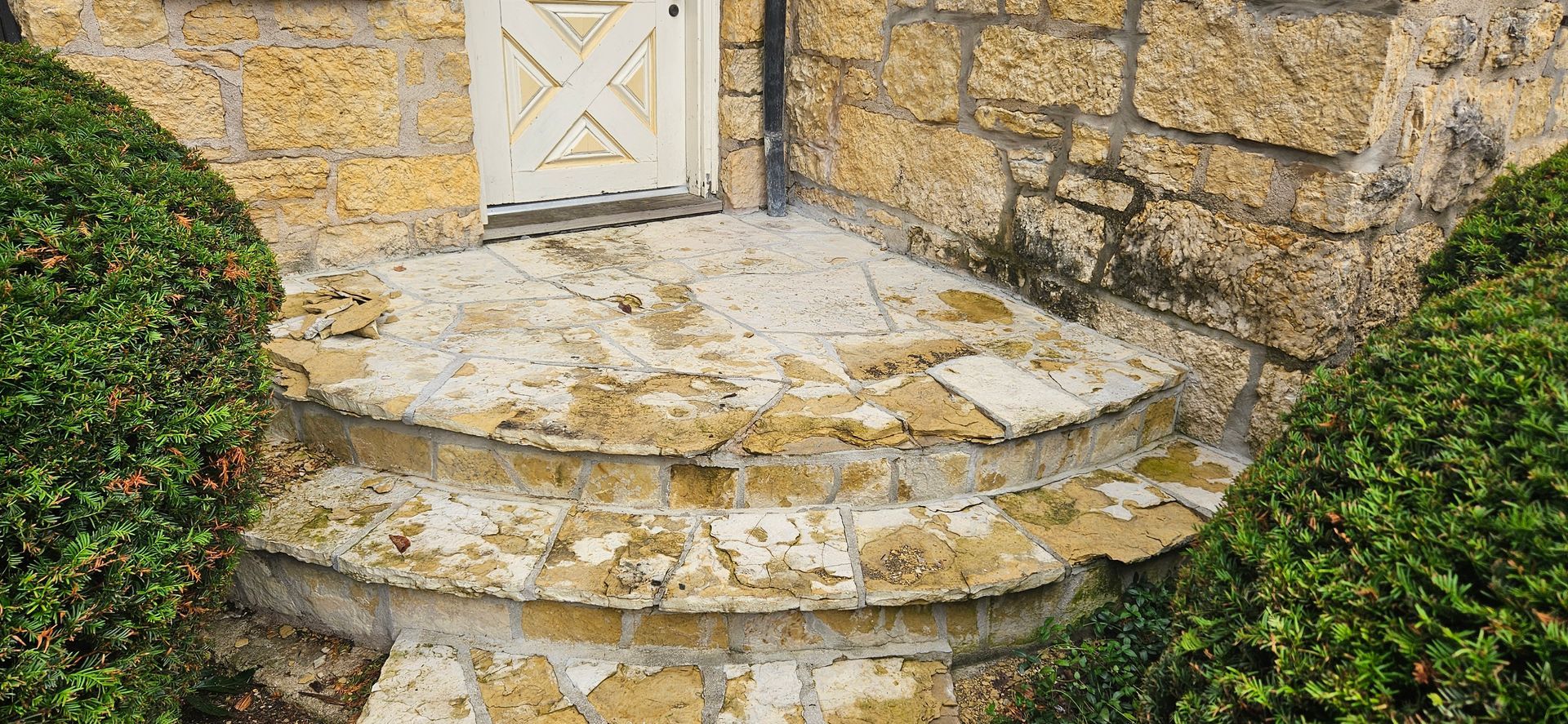 A stone staircase leading up to a stone building with a white door.