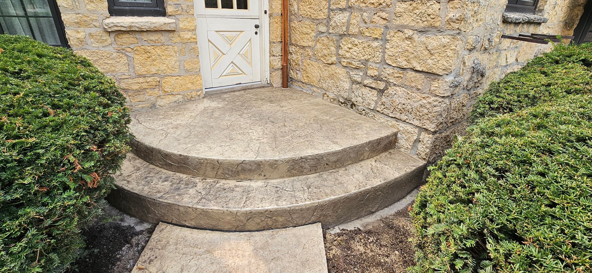 A stone house with a white door and steps leading up to it.