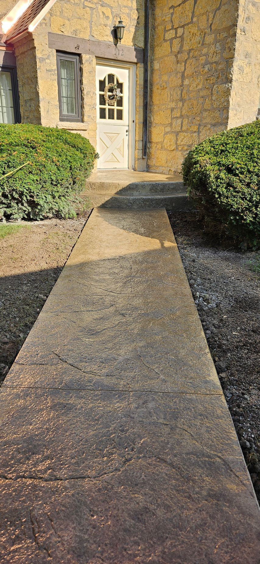 A concrete walkway leading to a house with a white door.