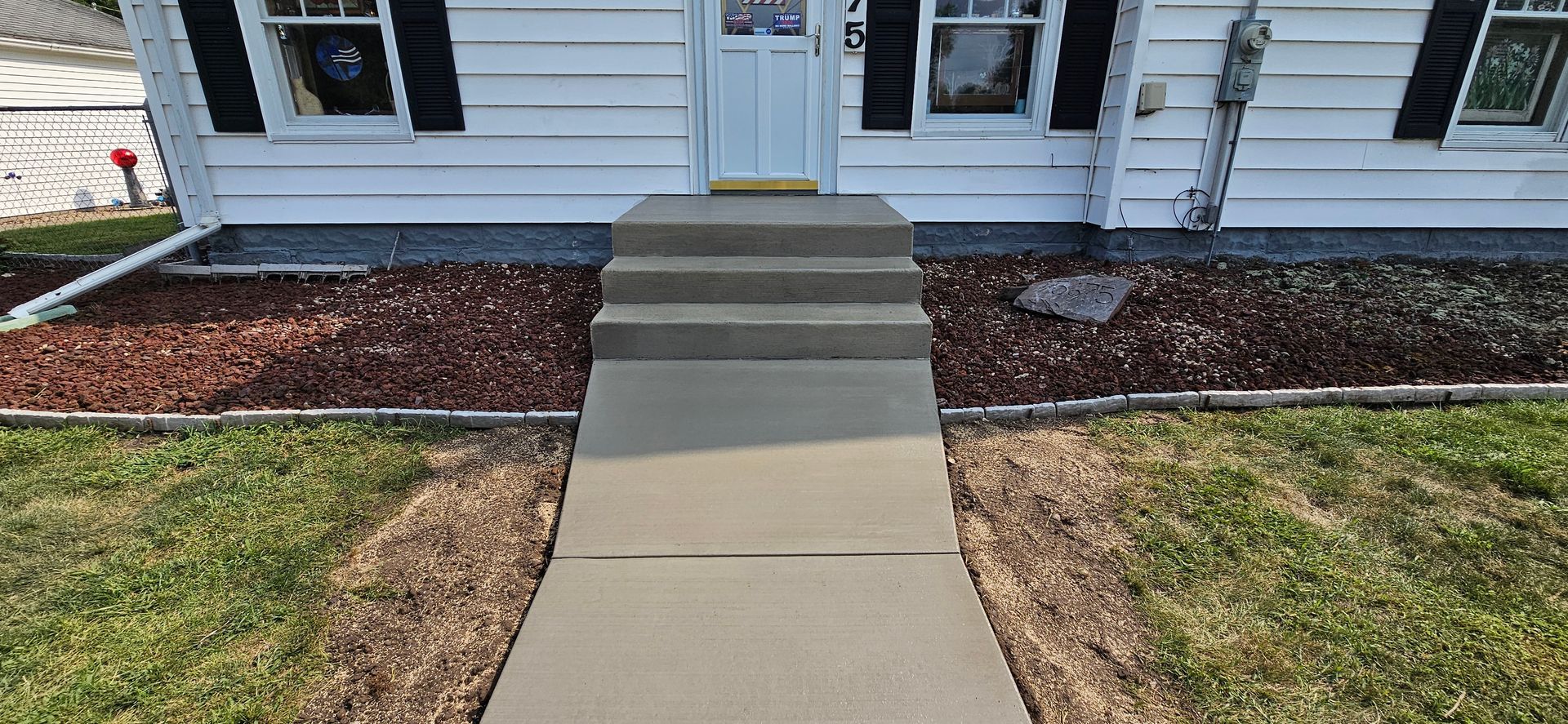 A concrete walkway leading to the front door of a house.