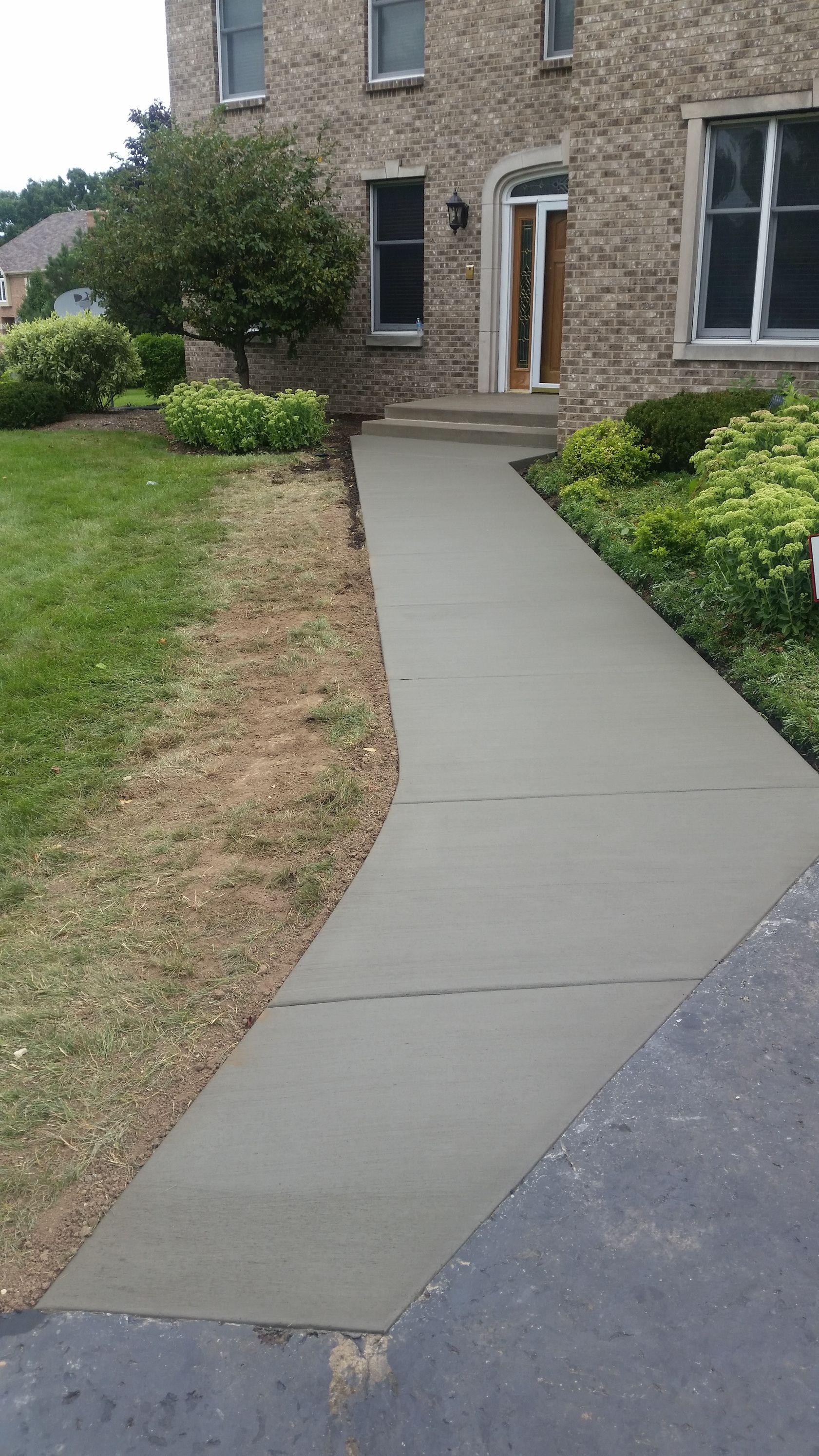 A concrete walkway leading to the front door of a house.