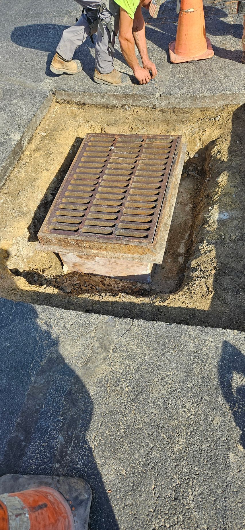 A manhole cover is being installed in a hole in the ground.