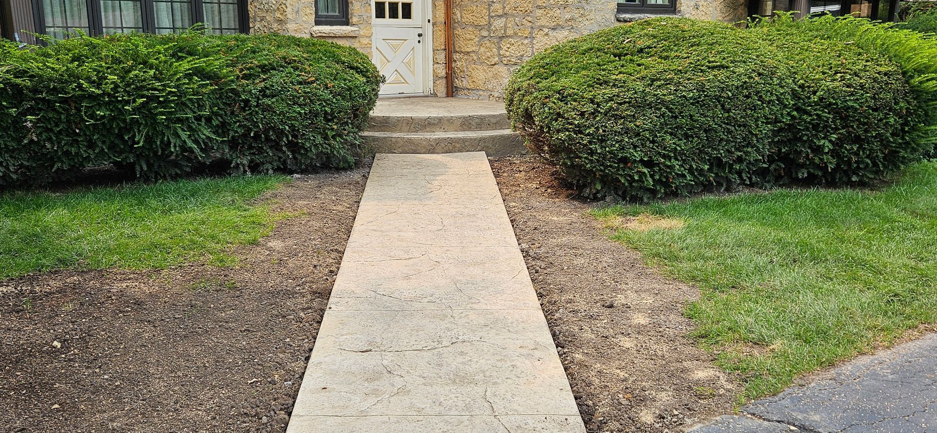 A concrete walkway leading to the front door of a house.