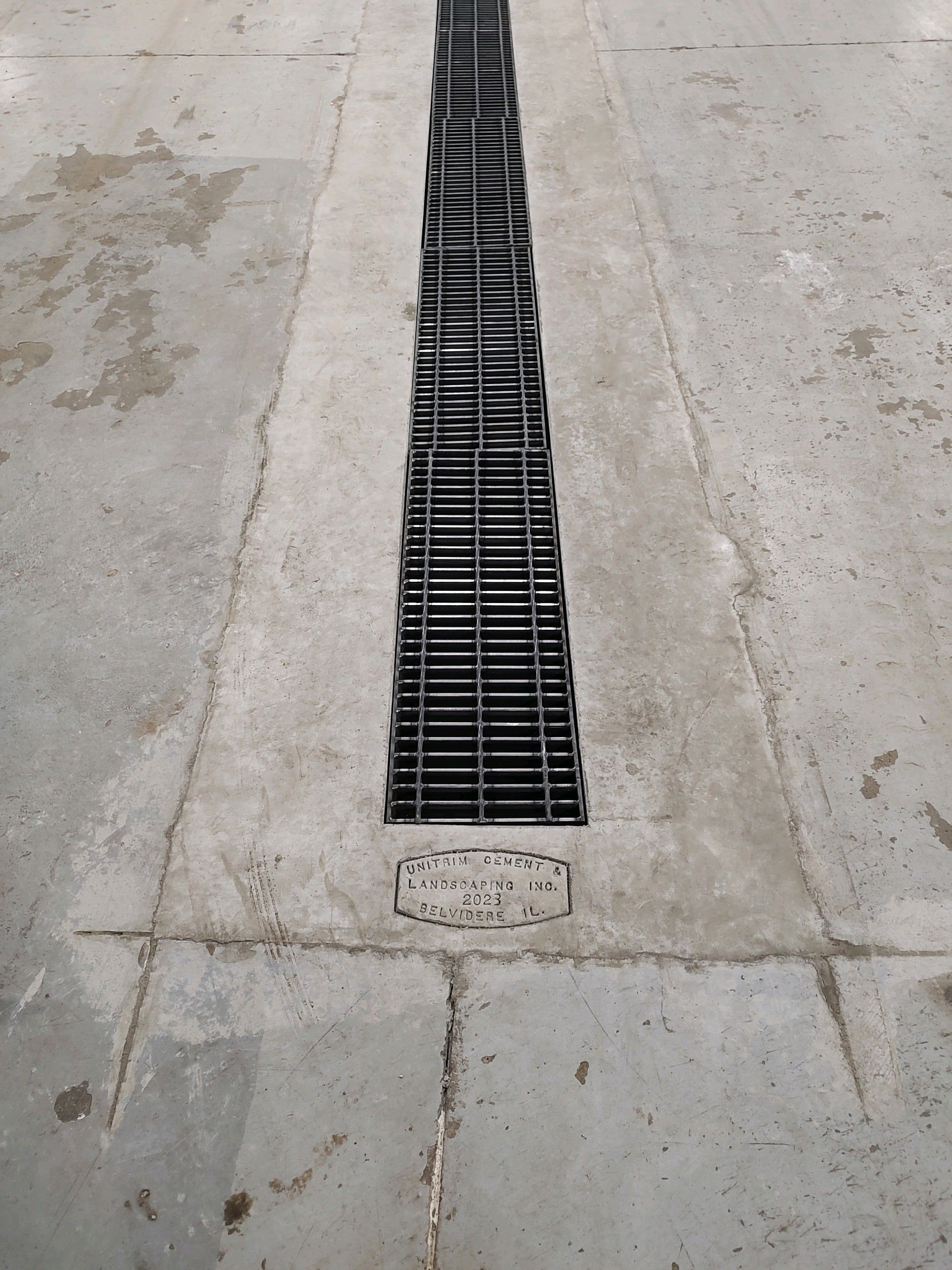 A drain on a concrete floor that looks like a guitar.