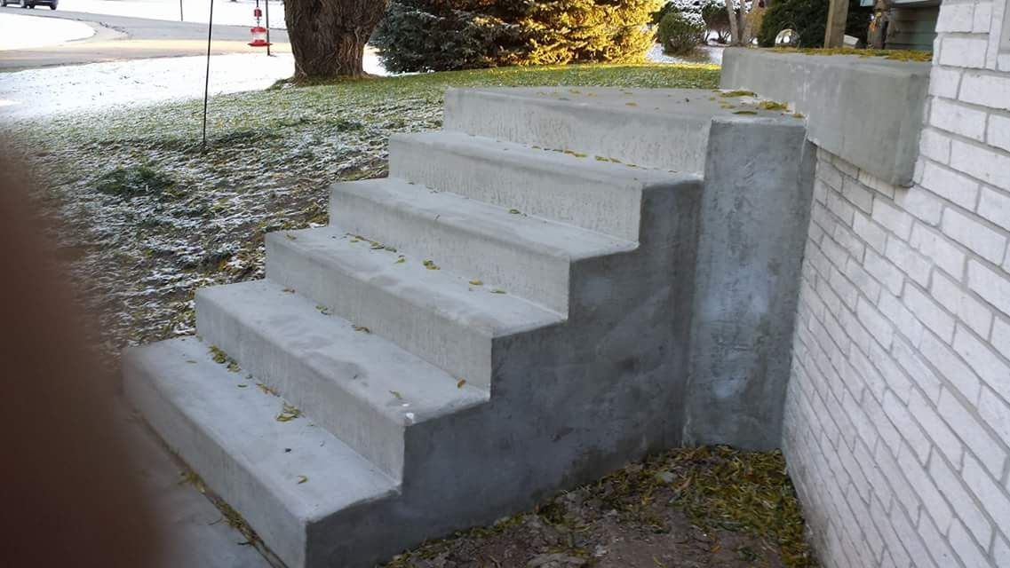 A set of concrete stairs leading up to a white brick building.
