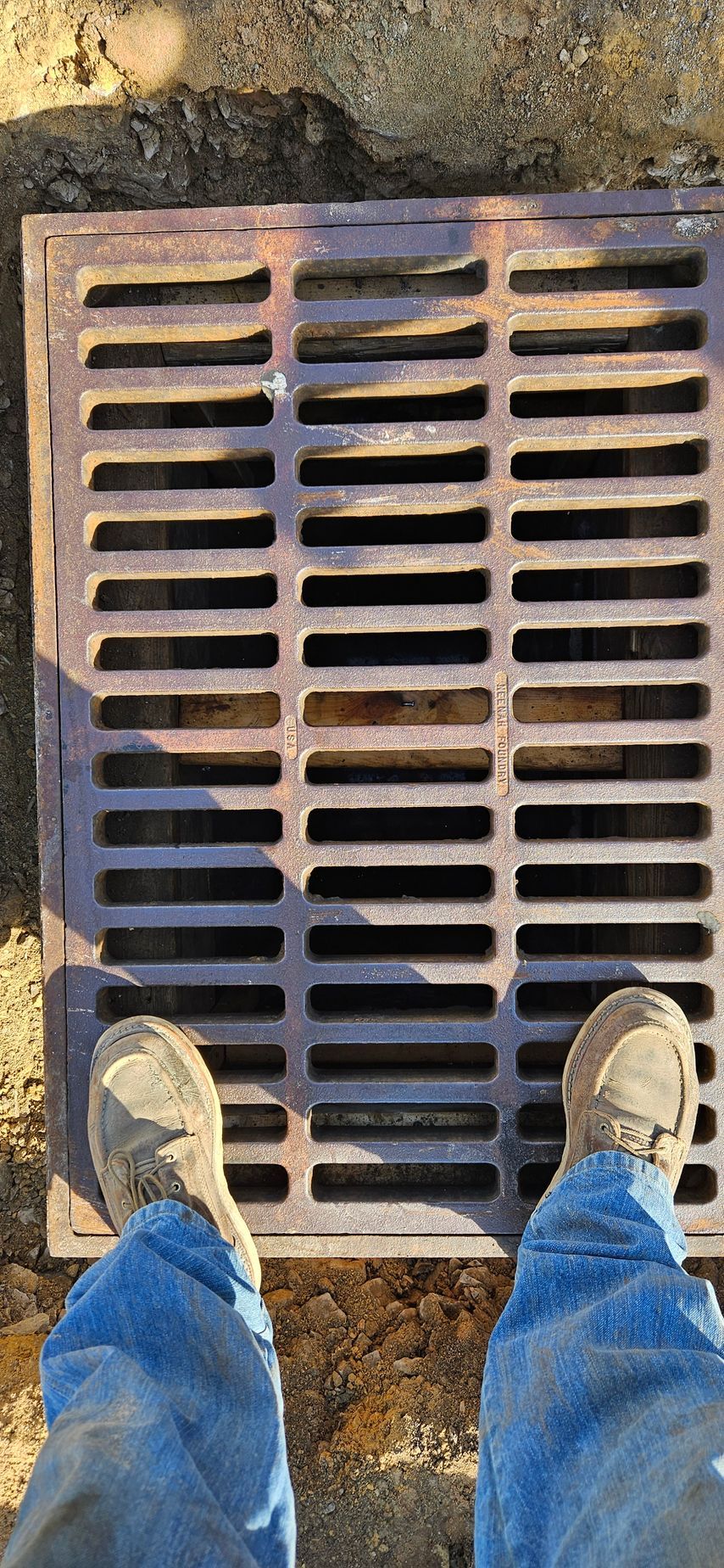 A person is standing next to a manhole cover.