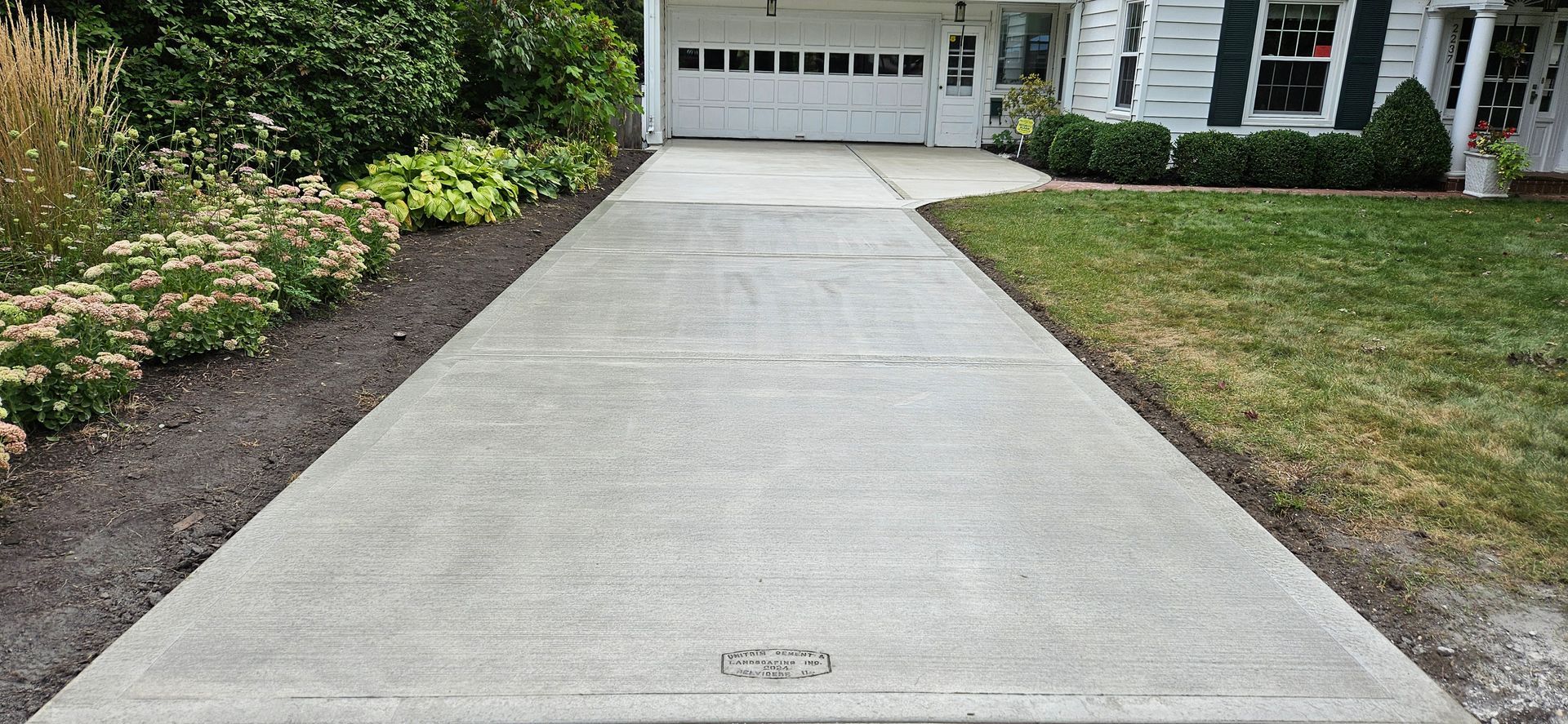 A concrete driveway leading to a house with a garage door.