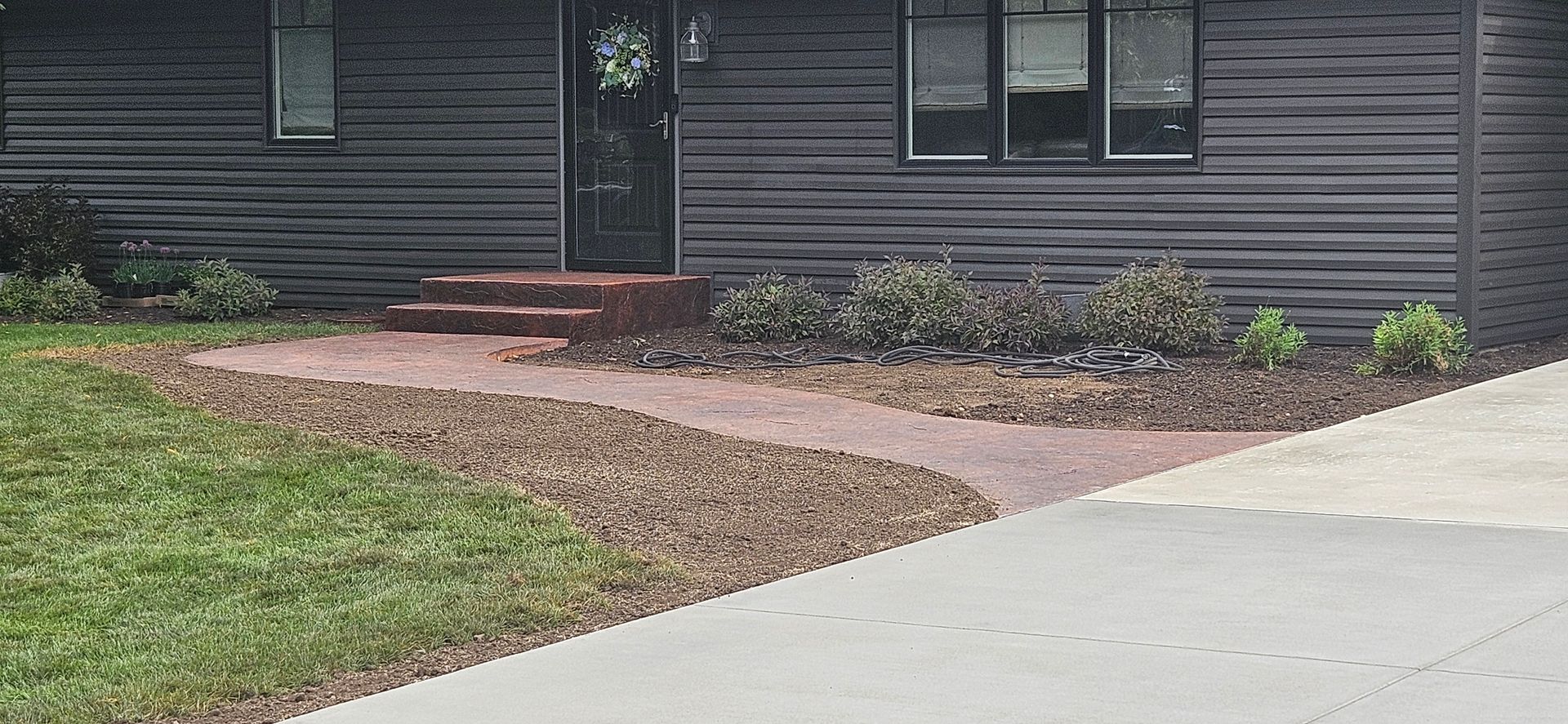 A black house with a brick walkway leading to the front door.