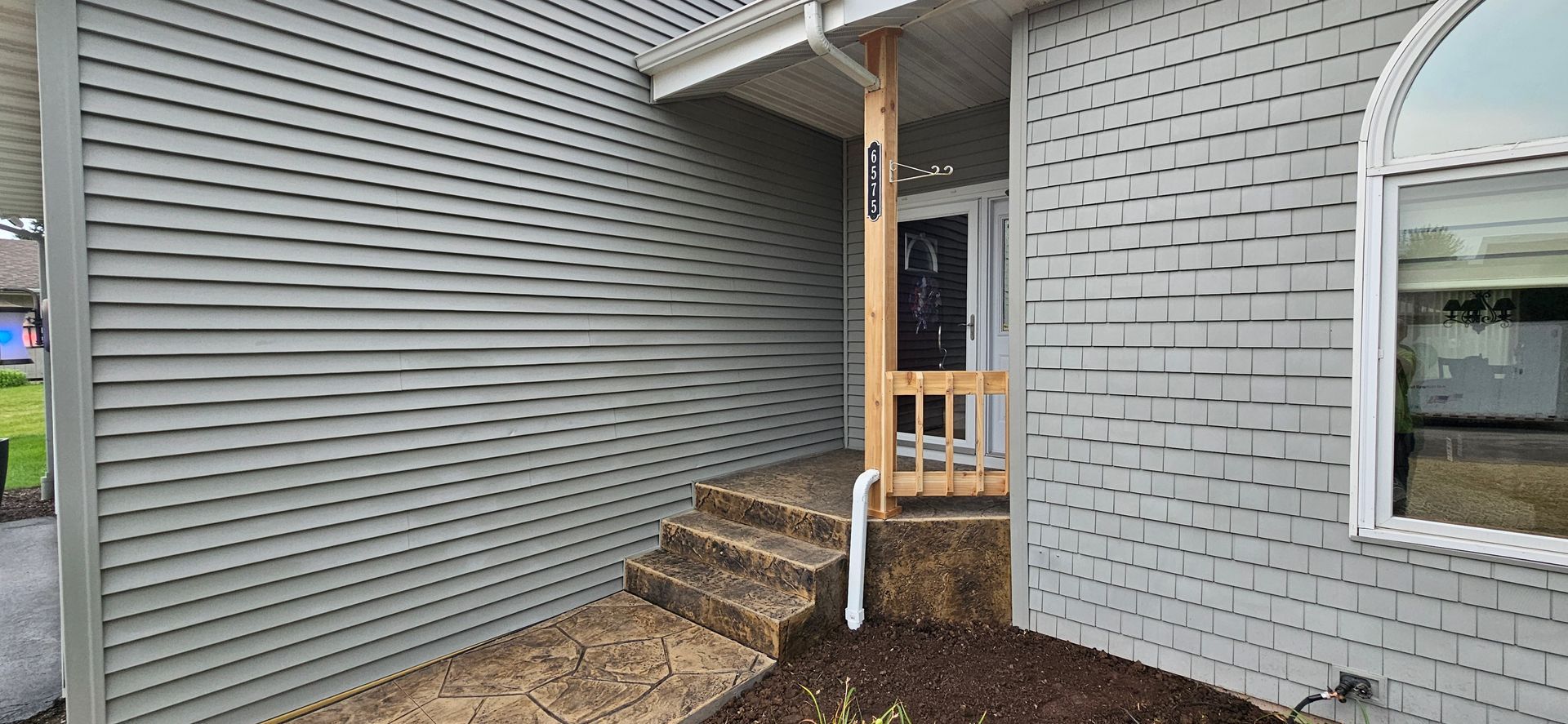 The front of a mobile home with a porch and stairs.