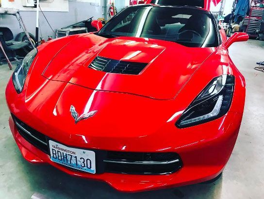 A red sports car with a license plate that says boh7130 is parked in a garage.