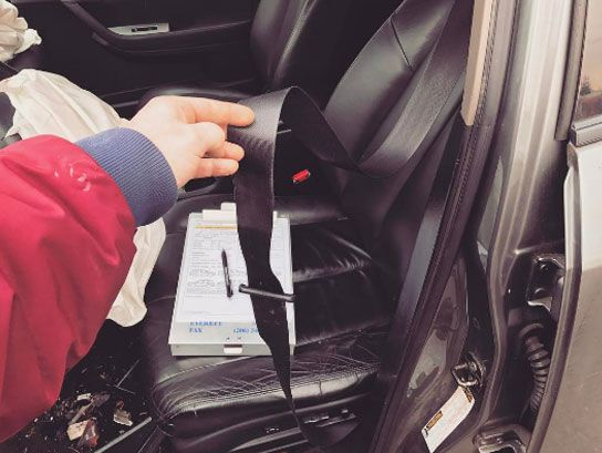 A person in a red jacket is putting a seat belt on a car seat