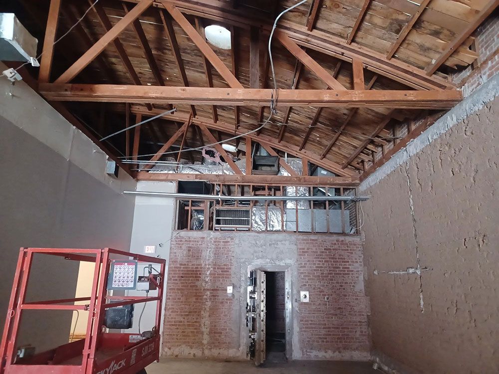 Interior view of a building with exposed wooden beams, a brick wall, and a red lift.