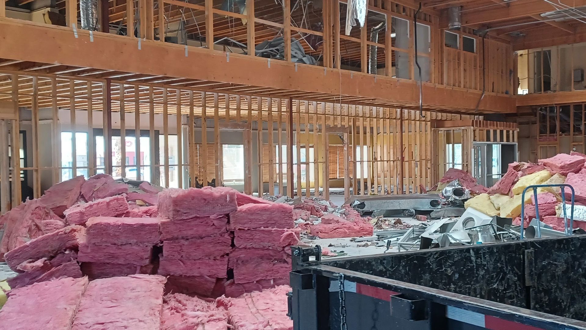 Interior of a building under construction, exposed wooden framework with pink insulation.
