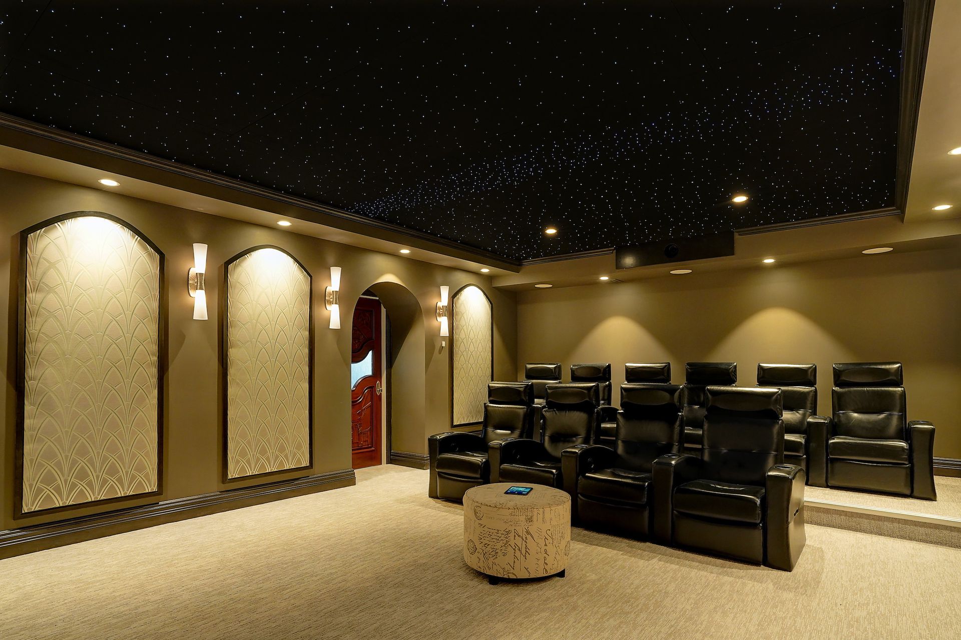 Home theater with star-lit ceiling, black recliners, beige carpet, and acoustic panels.