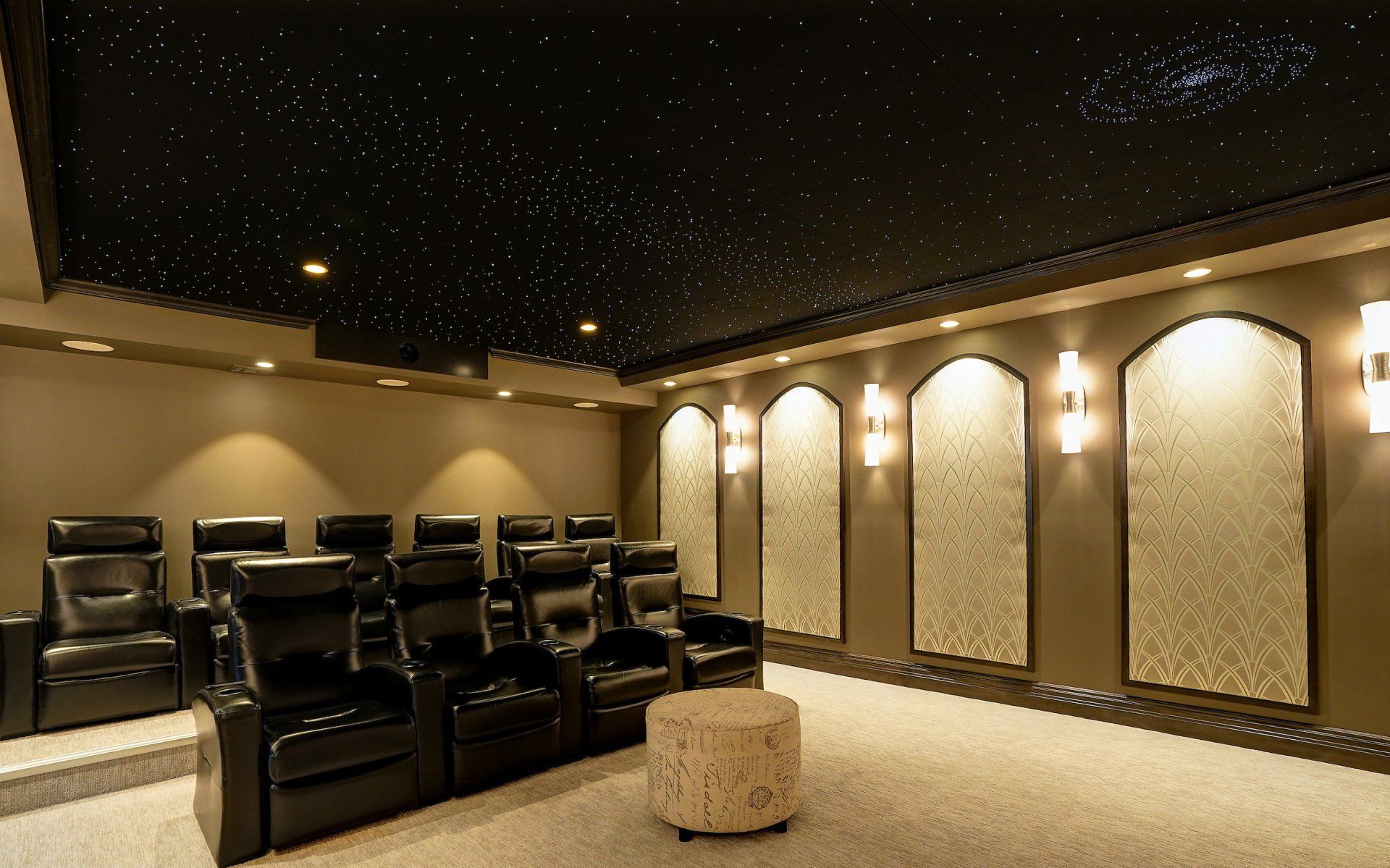 Home theater with black leather recliners, starry ceiling, and decorative wall panels.